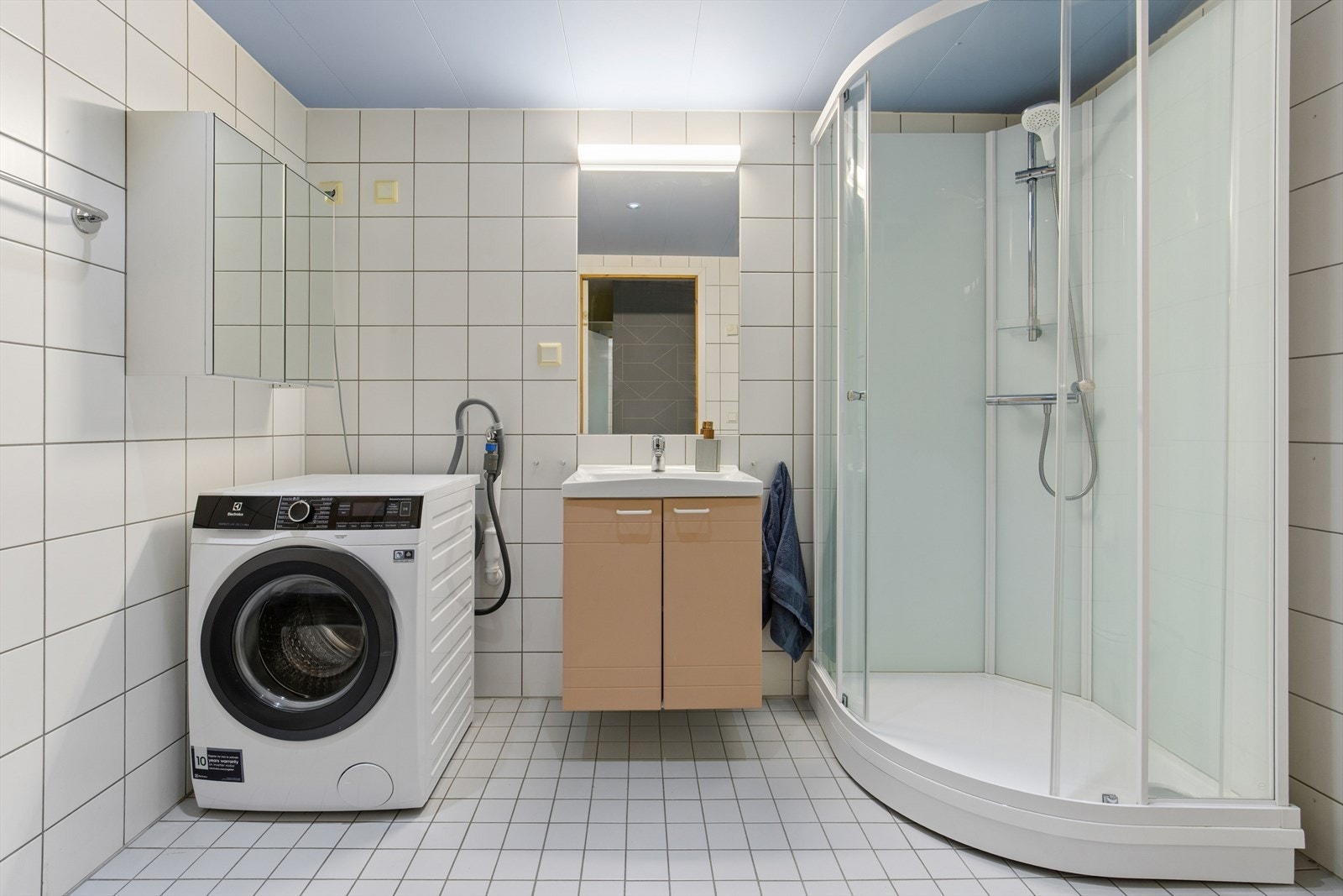 Flislagt bad med vannbåren gulvvarme, dusjkabinett og opplegg for vaskemaskin. Galleribilde