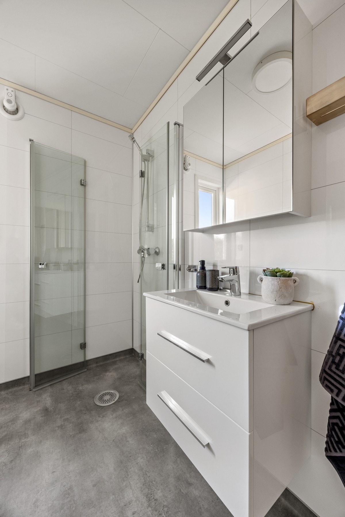 Badet er utstyrt med servantskap, innfellbare dusjdører og vegghengt toalett Galleribilde