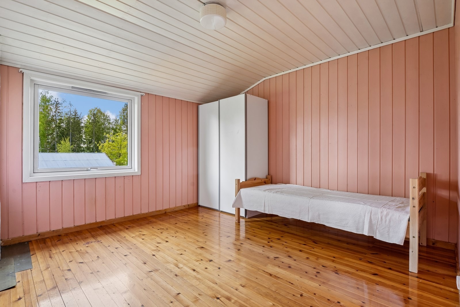 Soverom med vindu mot uteområdene og tradisjonelle overflater som trepanel og heltregulv. Galleribilde