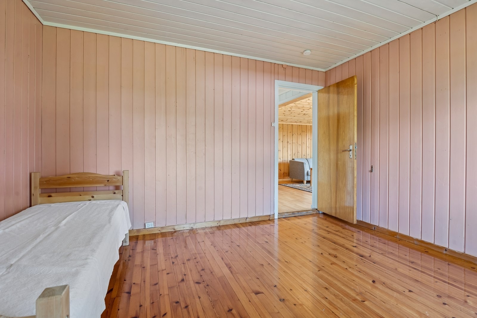 Soverom i 1. etasje med panelte vegger, tregulv og plass til seng og oppbevaringsmøbler. Galleribilde