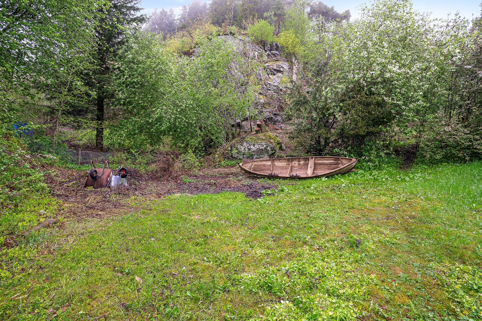 Tomten har et variert terreng med beplantning og naturlige elementer som steinformasjoner. Galleribilde