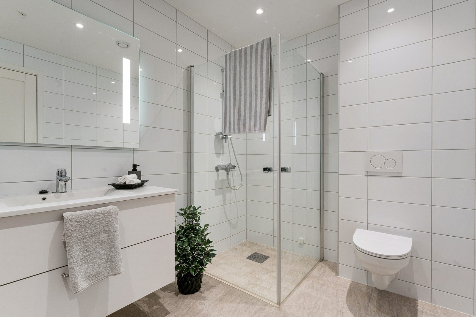 Badet byr blant annet på en elegant, nedsenket dusjsone med stilrene, vendbare glassdører for en mer plassbesparende løsning Galleribilde