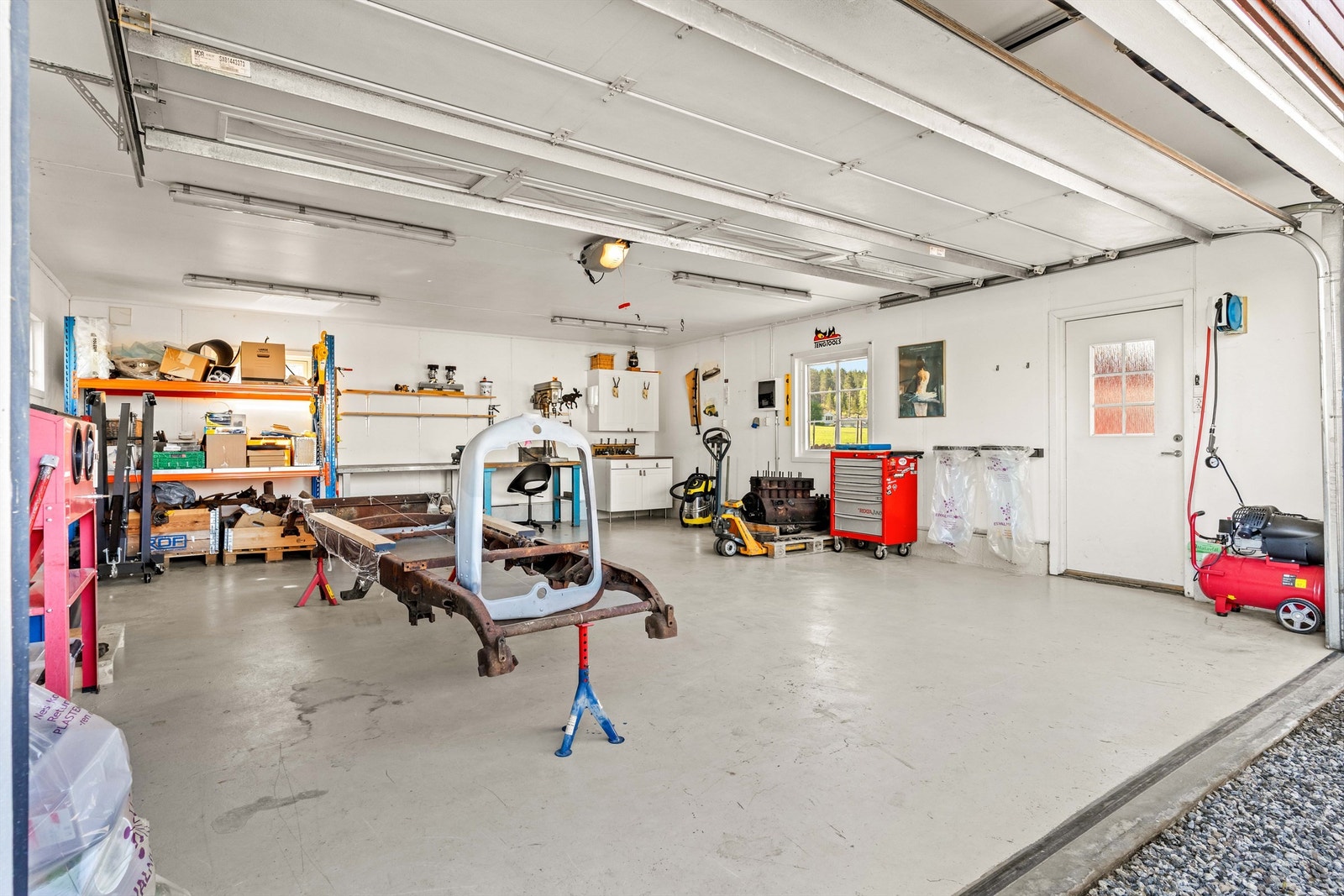 Stor, oppvarmet garasje med god plass til både bil og hobbyprosjekter. Ladepunkt for elbil er montert på ytterveggen. Galleribilde