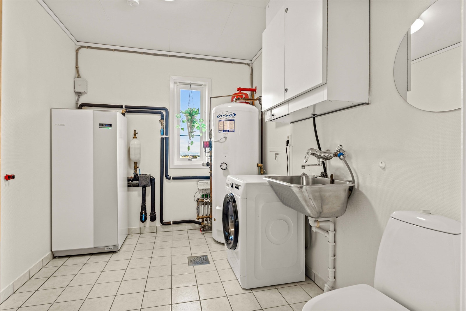 Separat vaskerom med flislagt gulv med varme. Her er boligens tekniske anlegg samlet, inkludert varmtvannsbereder og aggregat for balansert ventilasjon. Galleribilde