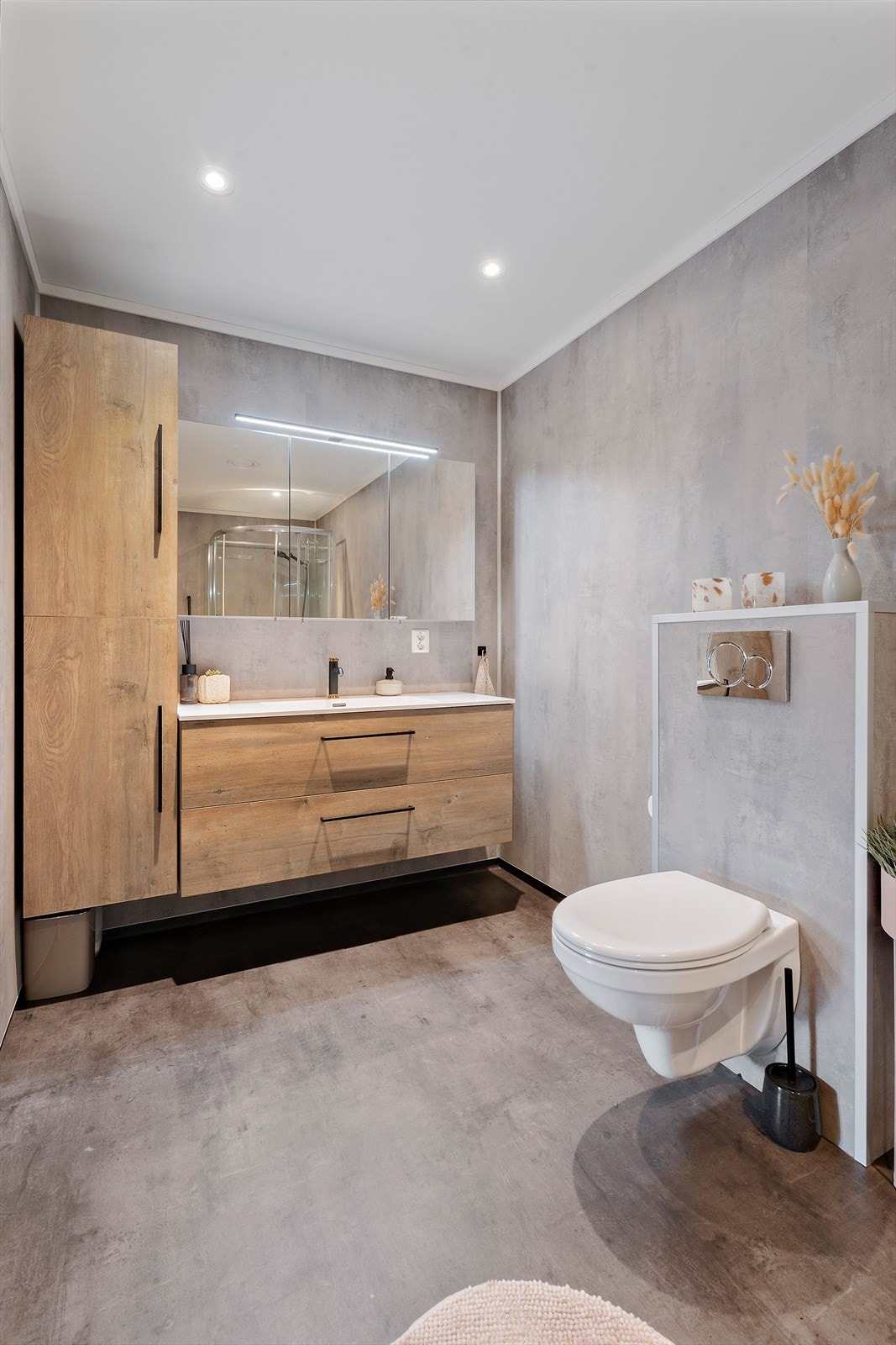 Badet har har innredning med nedfelt servant, veggmontert toalett, dusjkabinett. Spotter i taket , gulvarme i gulvet. Galleribilde