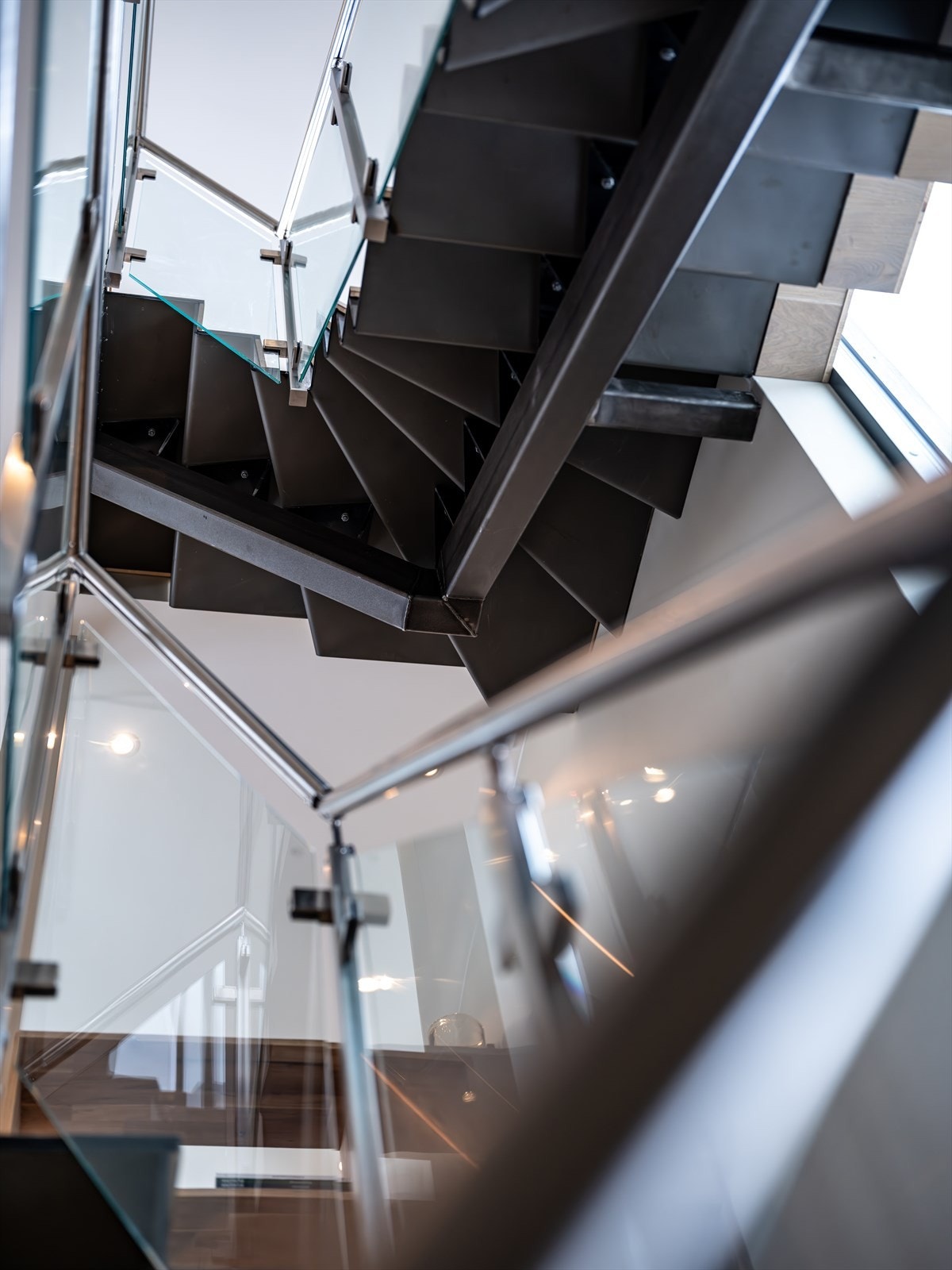 Trappen, som går gjennom alle etasjer, fungerer som et elegant midtpunkt i boligen og bidrar til en eksklusiv og sammenhengende romfølelse Galleribilde
