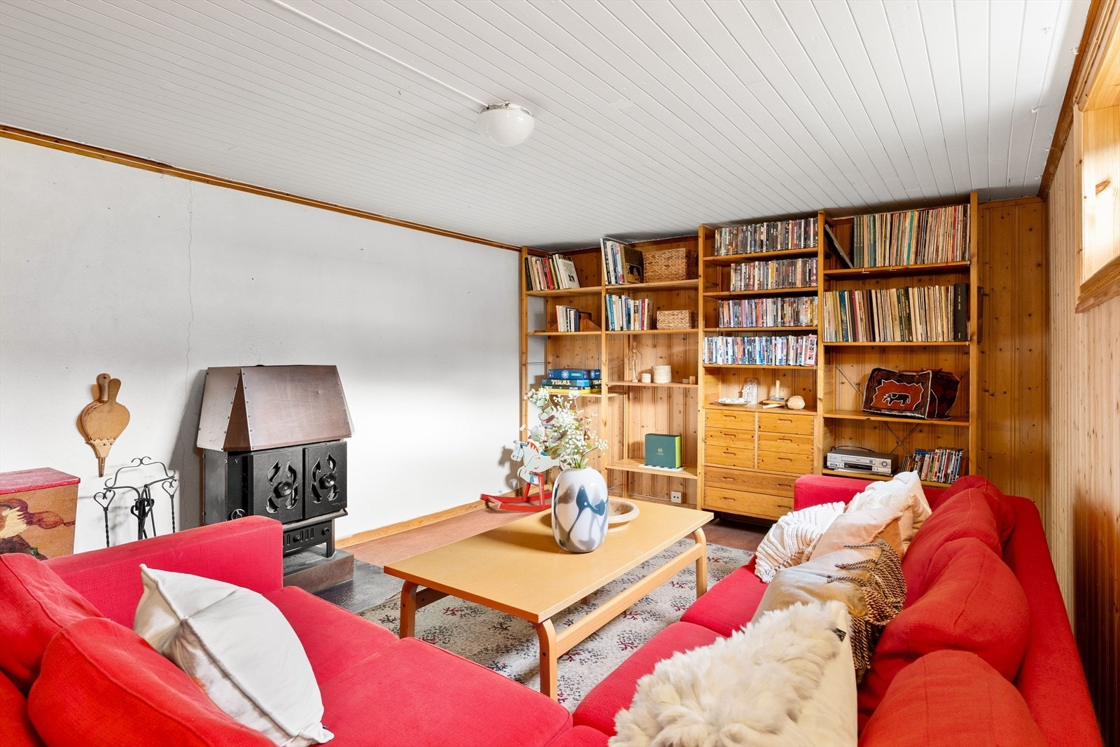 Rom innredet som kjellerstue er utstyrt med vedovn, som bidrar til en lun atmosfære. Galleribilde