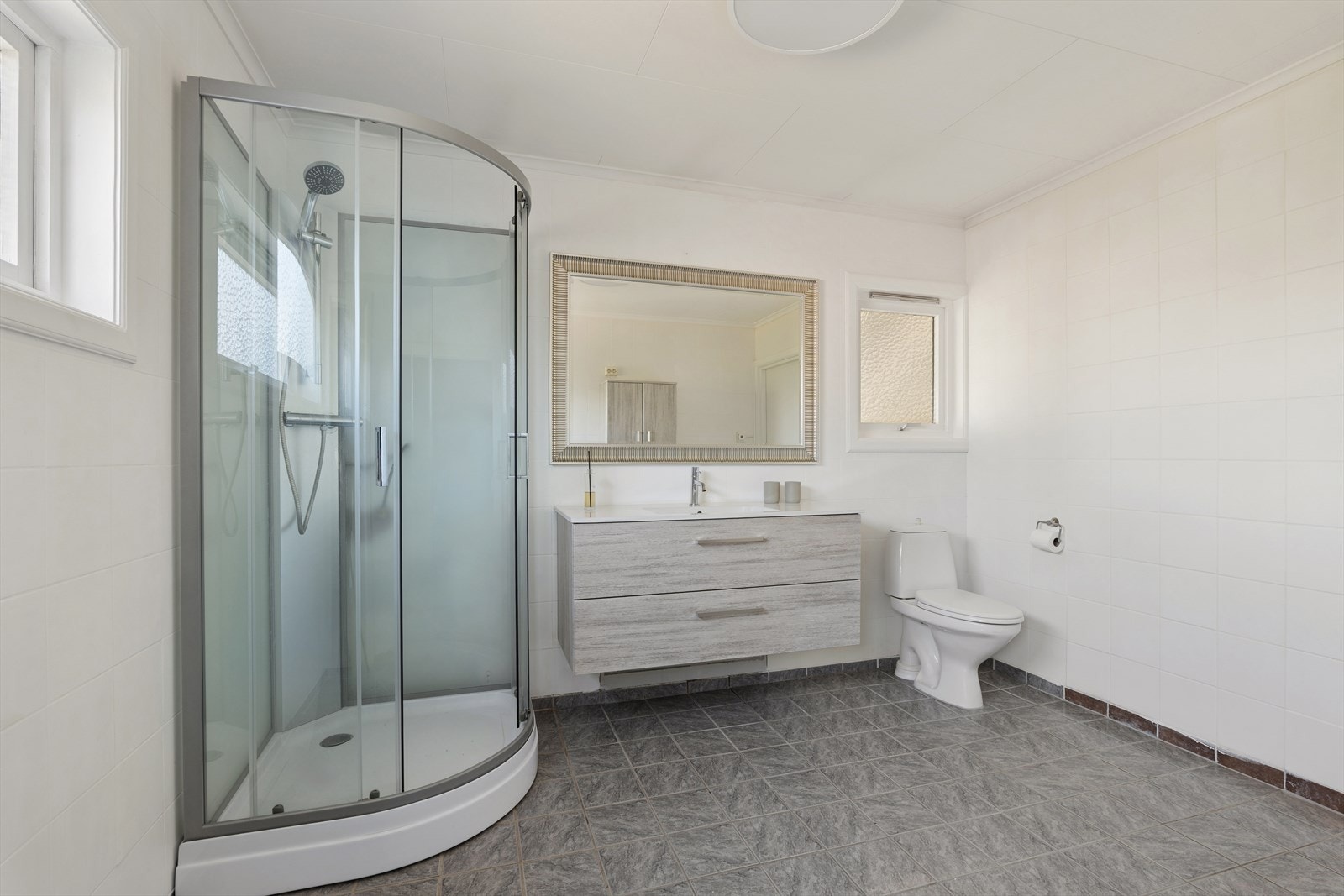 Badet har flislagt gulv med varmekabler og malte veggflater Galleribilde