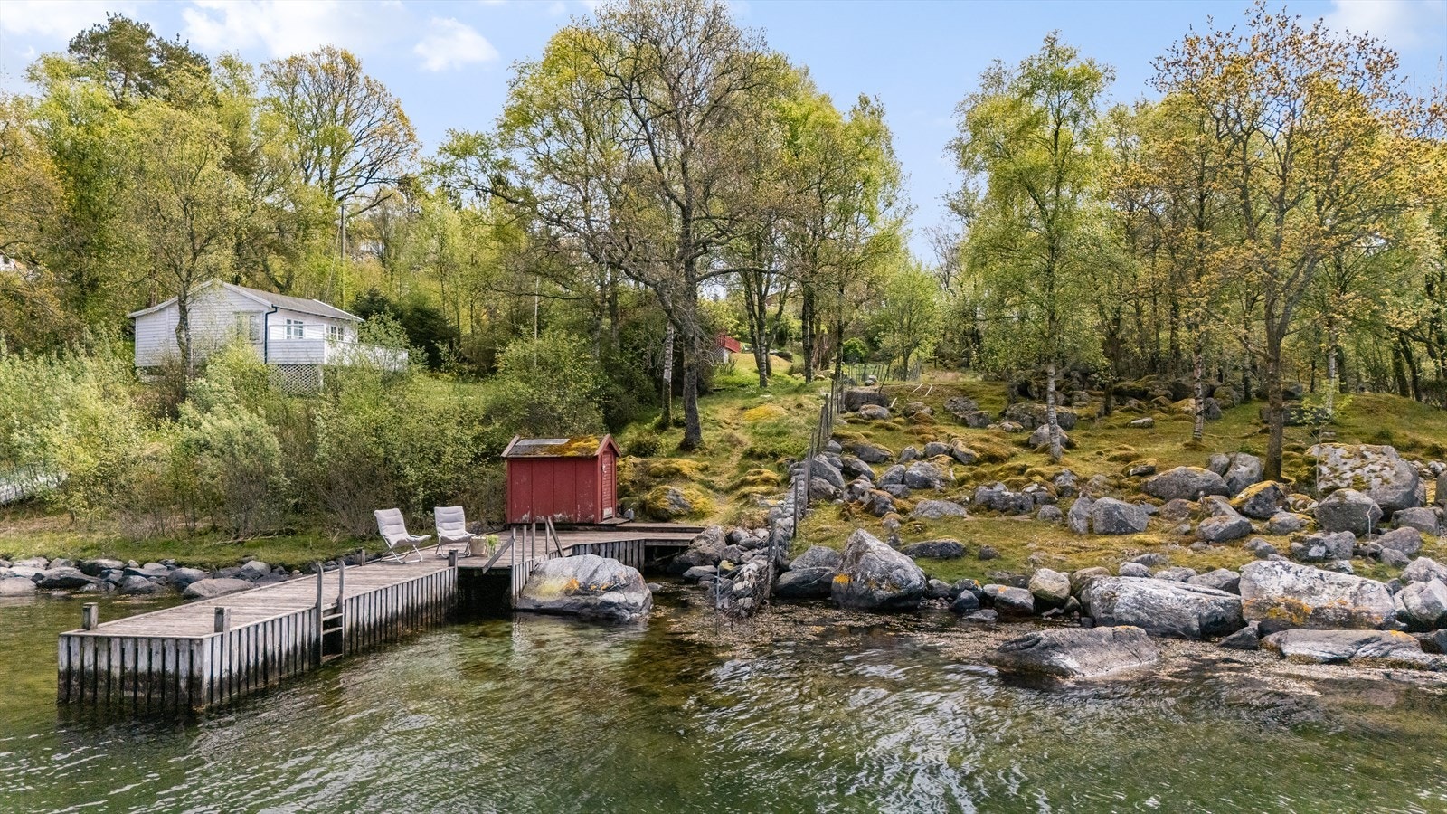 Nede ved sjøen ligger en enkel sjøbod med tilhørende brygge. Galleribilde