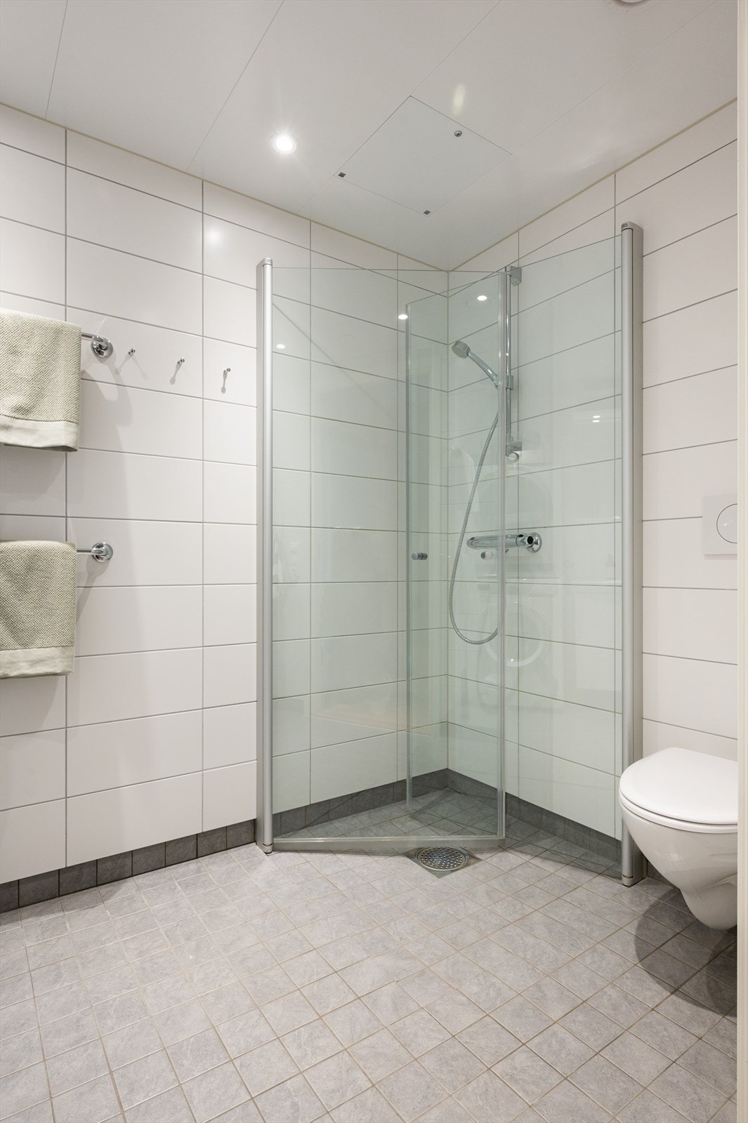 Flislagt gulv med varme, flislagte vegger og himlingsplater med downlights. Galleribilde