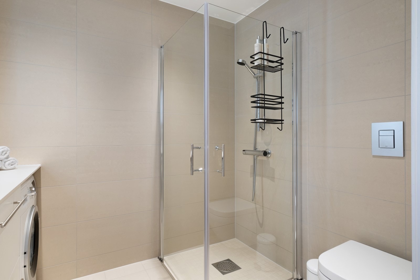 Badet er praktisk og smakfullt utforma, med toalett, dusjhjørne, opplegg for vaskemaskin, spegl med lys og servantmøbel. Det er montert spotlys i taket for god belysning. Galleribilde