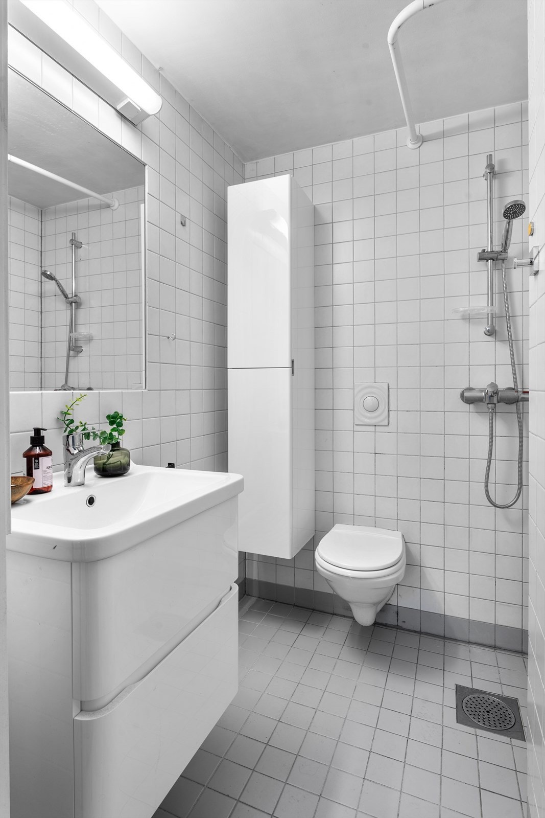 Badet har vegghengt servantinnredning av god størrelse, innfelt speil med overbelysning, vegghengt toalett og dusj. Galleribilde
