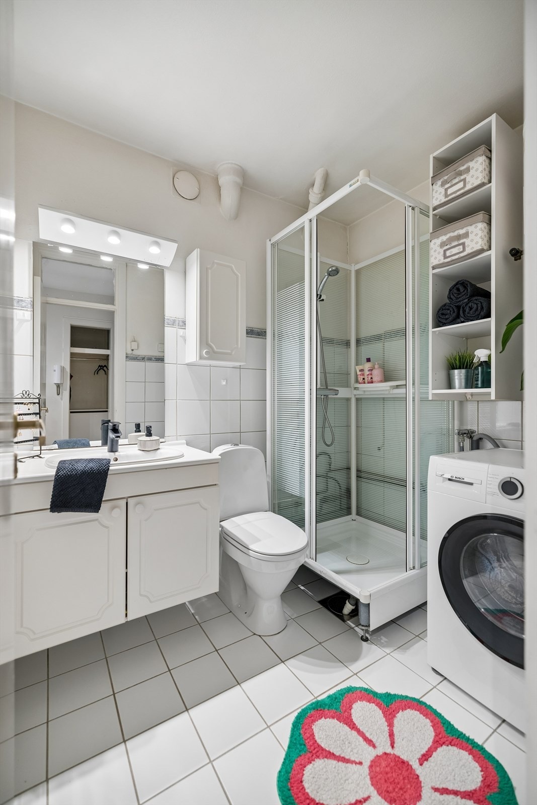 Badet er utstyrt med dusjkabinett, servant med oppbevaring og speil med belysning. Galleribilde