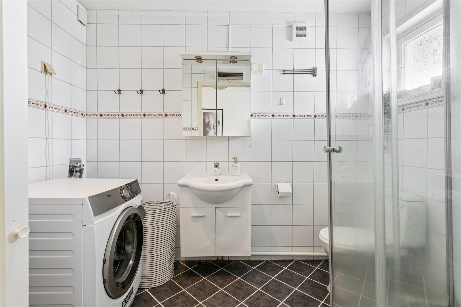 Eldre flislagt bad fra ukjent årstall. Det er vaskemaskin på badet som medfølger. Galleribilde