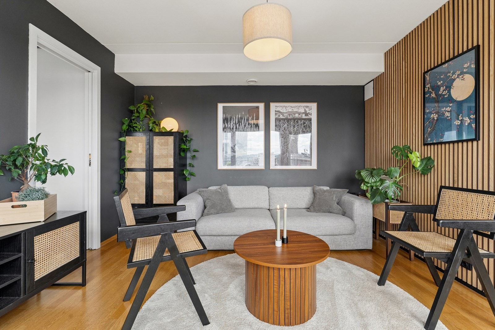 En lun og stilren stue med moderne preg, hvor gjennomgående materialvalg og en dekorativ vegg skaper en eksklusiv atmosfære. Galleribilde