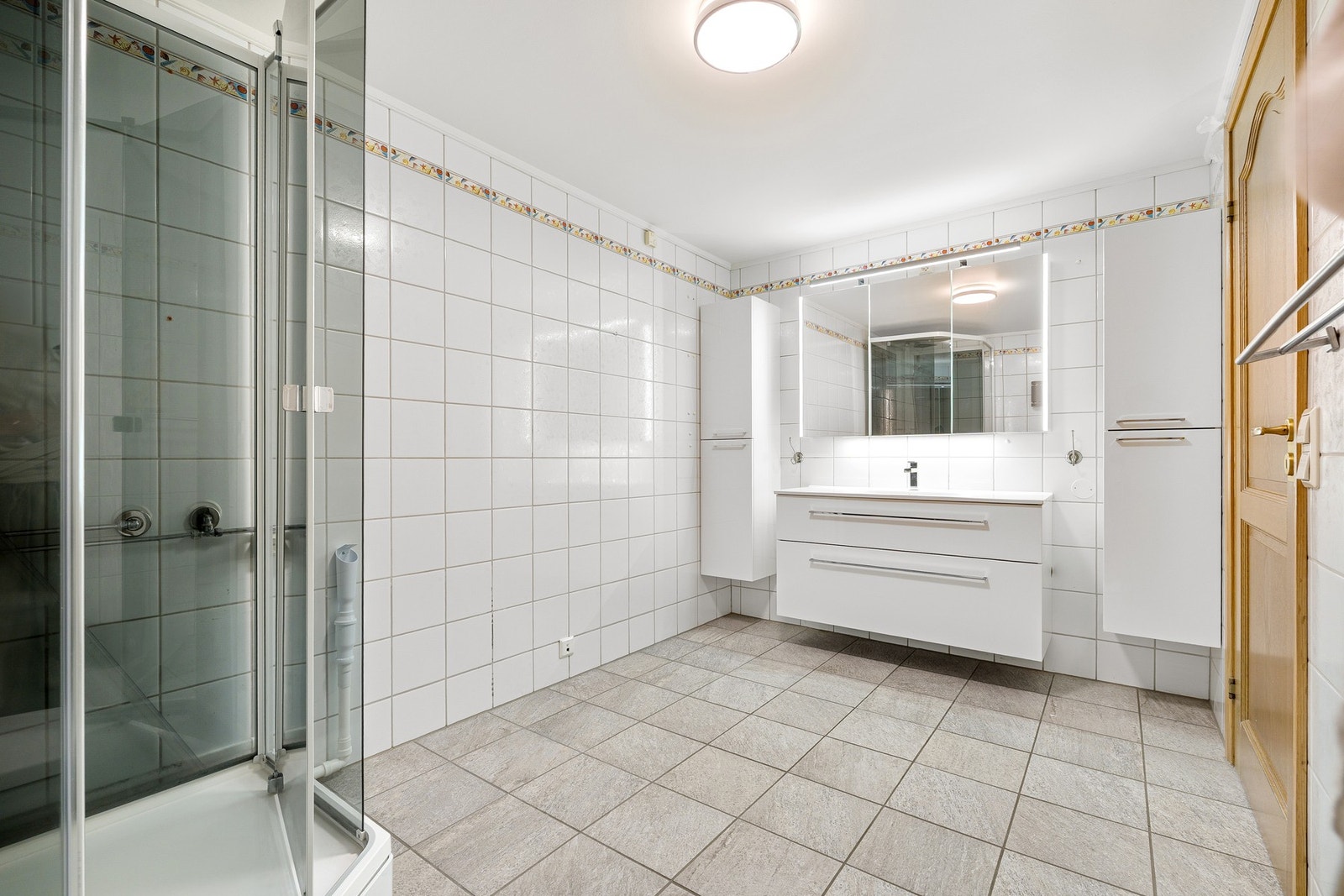 Badet måler 8 kvm og har flislagte overflater samt dusjkabinett. Galleribilde