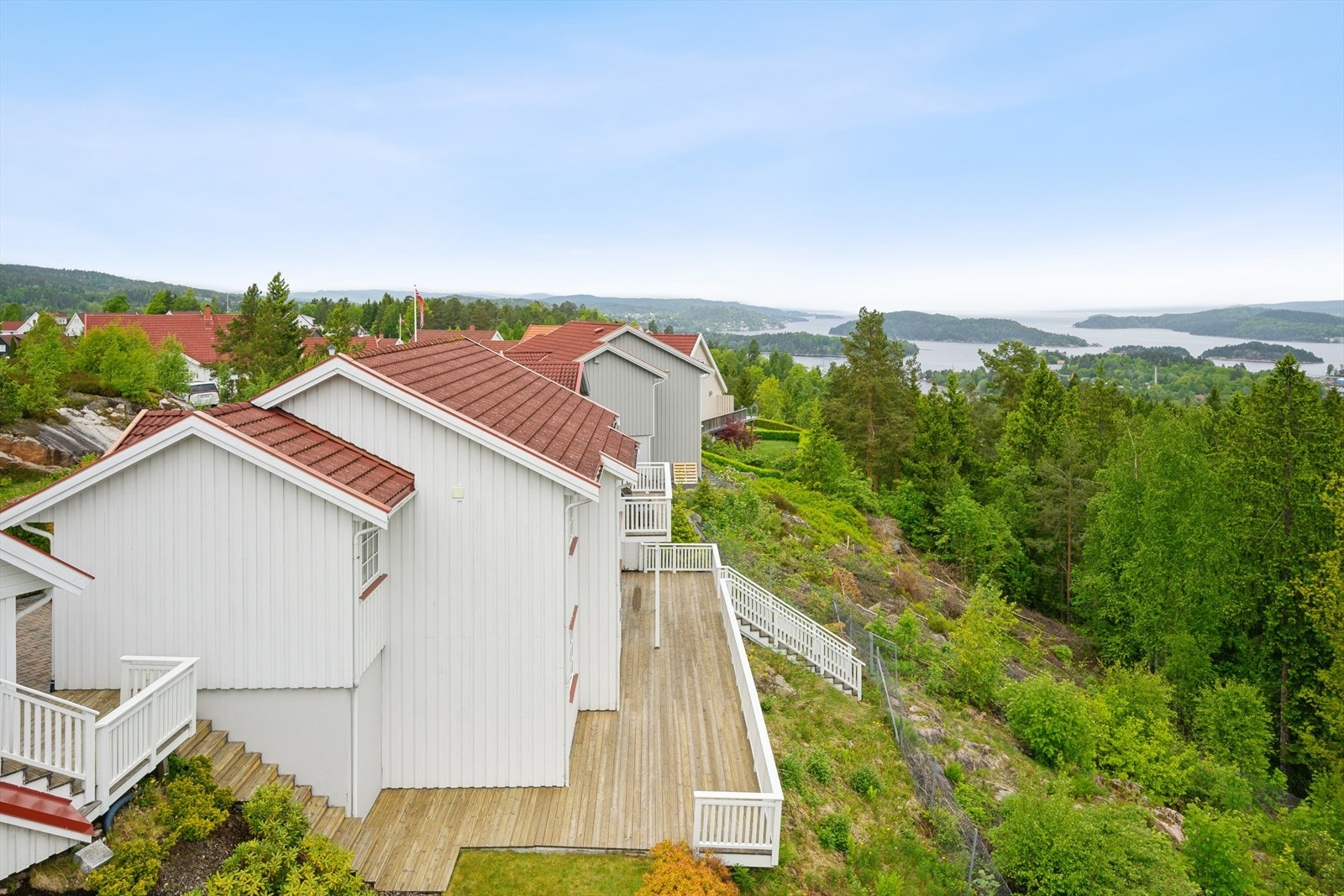 Boligen ligger høyt og fritt i et skrånende terreng, med utsikt over nærområdet og fjorden. Galleribilde
