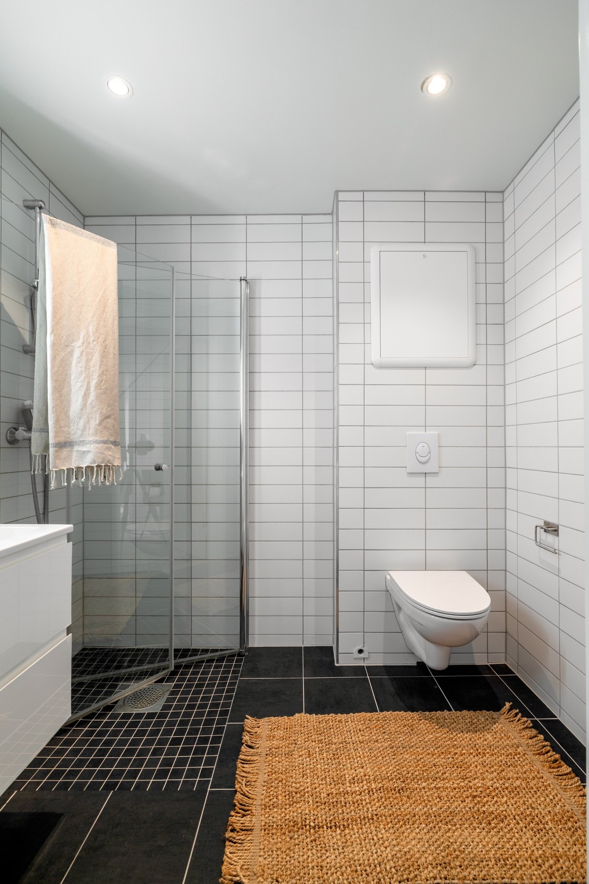 Badet er flislagt med grå fliser på gulv og hvite fliser på veggene Galleribilde