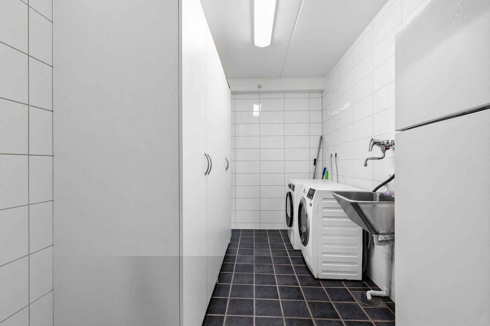 Separat vaskerom med flislagt gulv, varmekabler, skyllekar og opplegg for vaskemaskin. Galleribilde