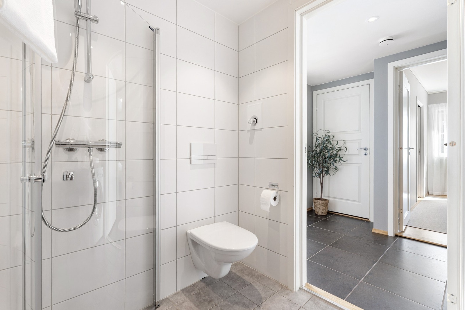 Badet er utstyrt med vegghengt WC, servant, dusjhjørne med innfellbare dører og opplegg for vaskemaskin. Galleribilde