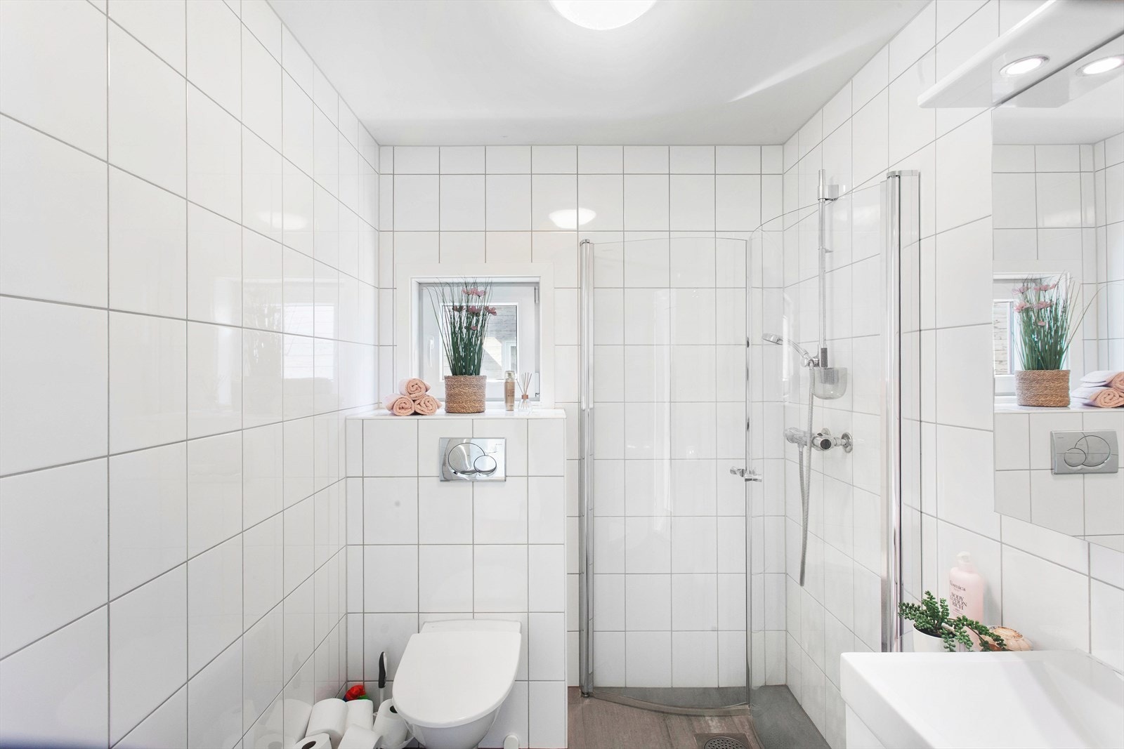 Badet i 2 etasje er stilrent innredet med flislagte gulv og vegger. Rommet er utstyrt med moderne dusjhjørne, toalett og servant. Badet fremstår som lyst, innbydende og trivelig. Galleribilde