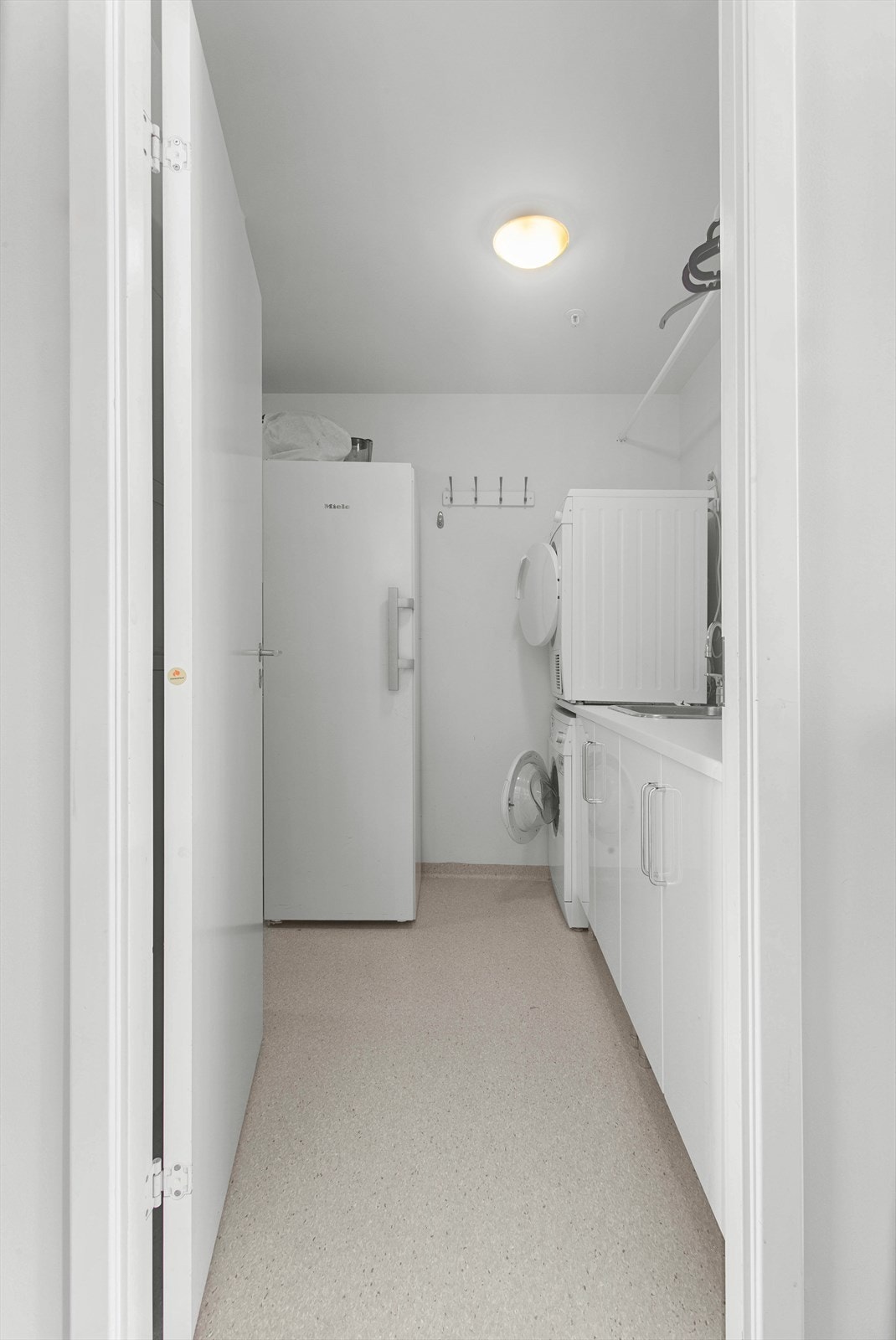 Praktisk vaskerom med gulvbelegg, opplegg for vaskemaskin og balansert ventilasjon. Det er også en god oppbevaringsplass, både med skyvedører og under og overskaper. Galleribilde