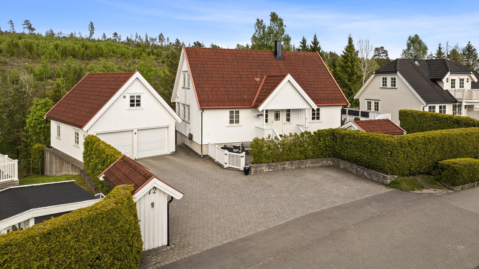 Eiendommen har en stor, belegningssteinbelagt gårdsplass og en separat leilighet i underetasjen. Galleribilde