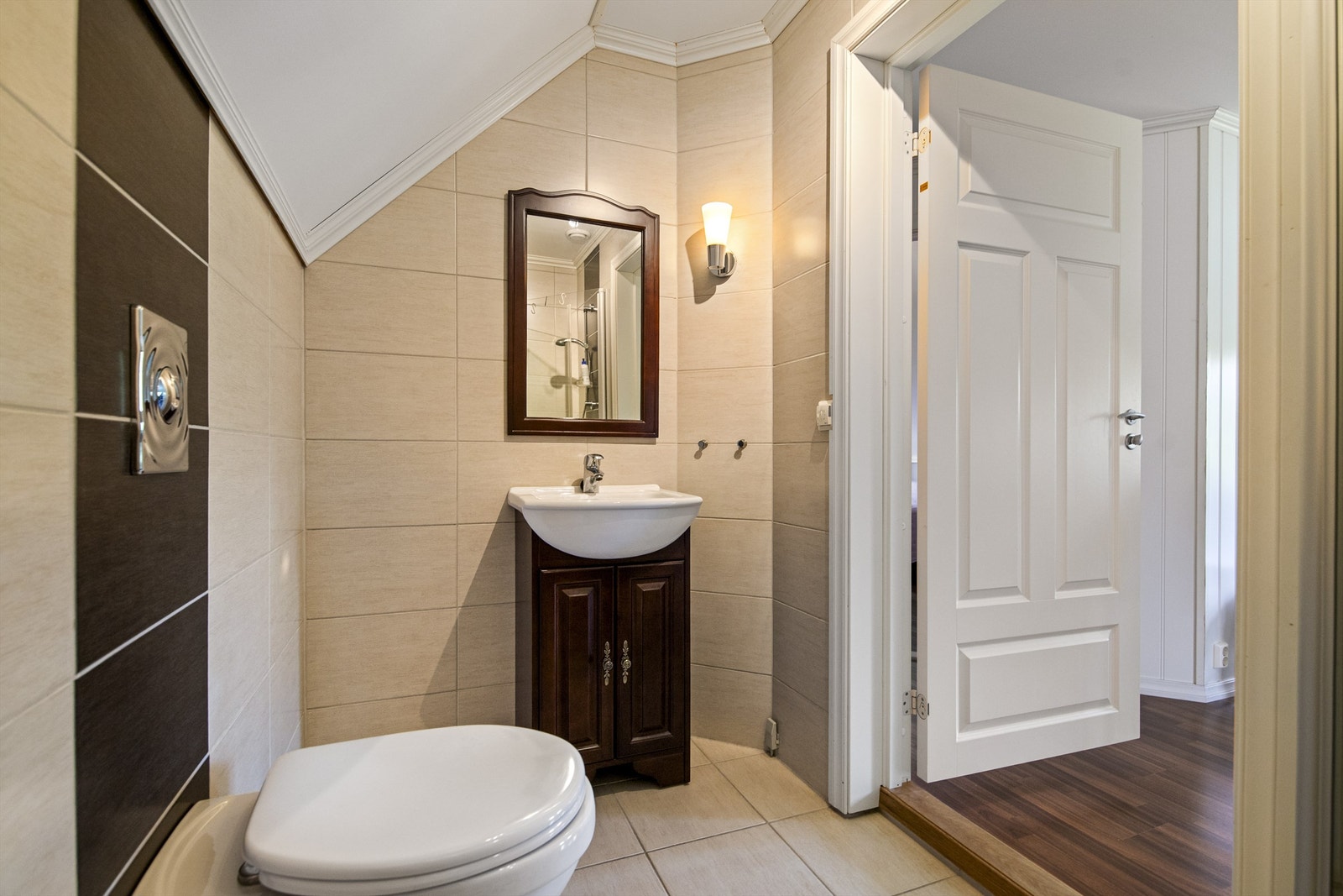 Badet er utstyrt med vegghengt toalett, servant med underskap og dusj. Galleribilde