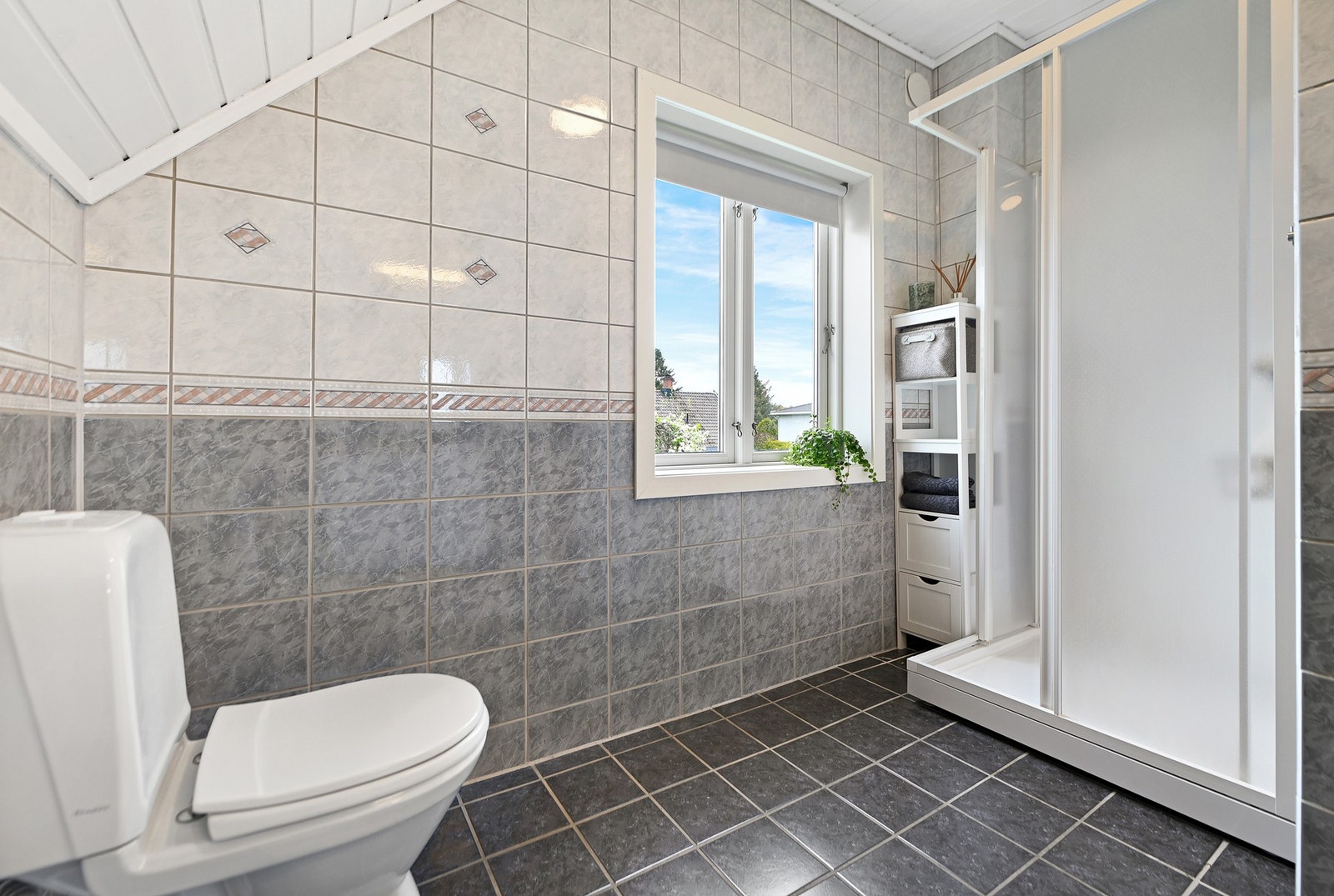 Rommet har dusjkabinett, gulvstående wc, servantskap og speil. Galleribilde
