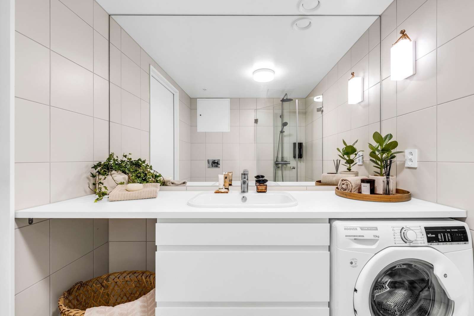 Badet har praktiske løsninger som nisje til vaskemaskin og tørketrommel, oppbevaringsplass i badromsmøbel og heldekkende speil. Galleribilde