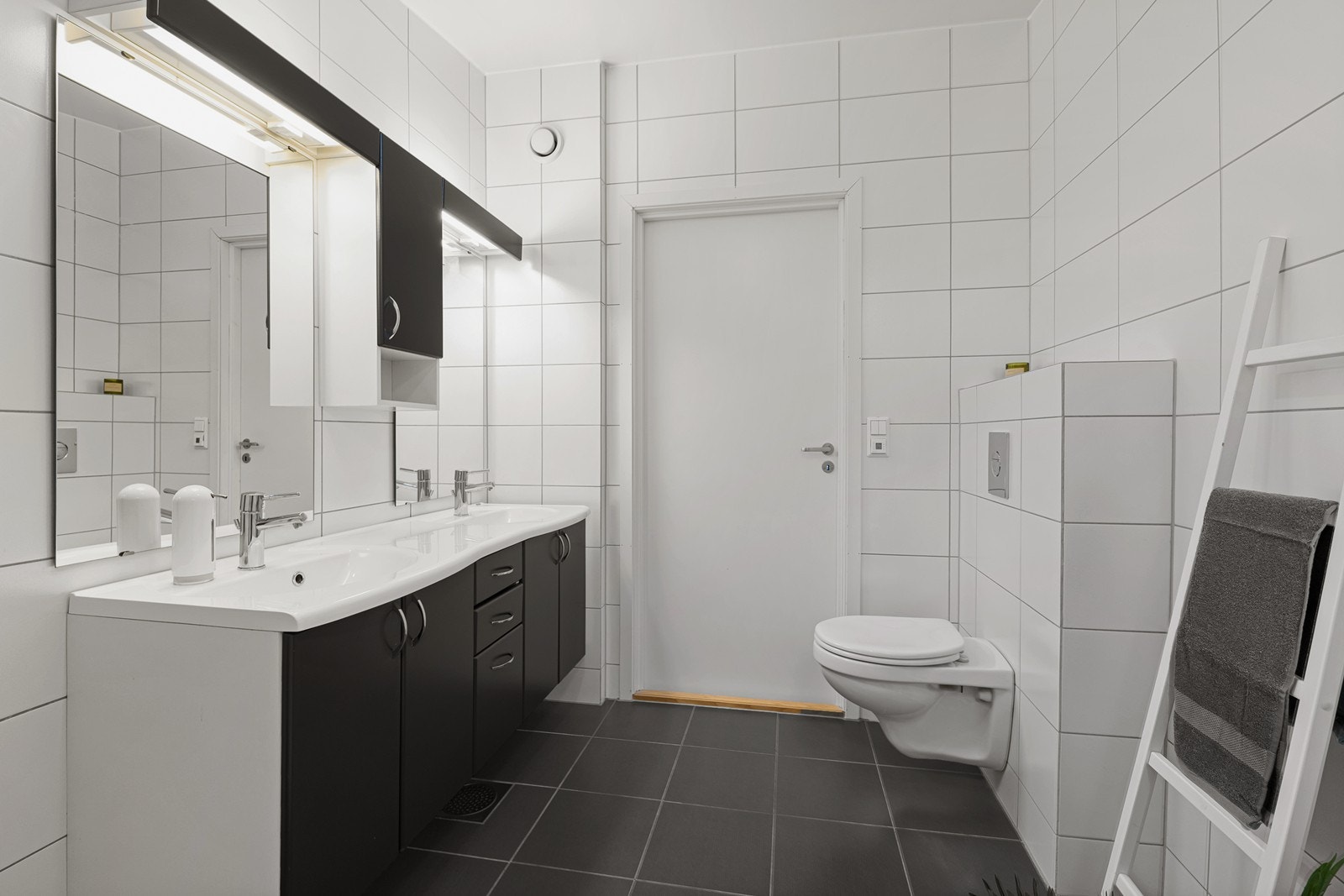 Badet har dobbel servant nedfelt i innredning med både skuffer og skap, som gir gode oppbevaringsmuligheter. Det er speil over innredningen som gir et lyst og romslig uttrykk til badet. Vegghengt toalett. Galleribilde