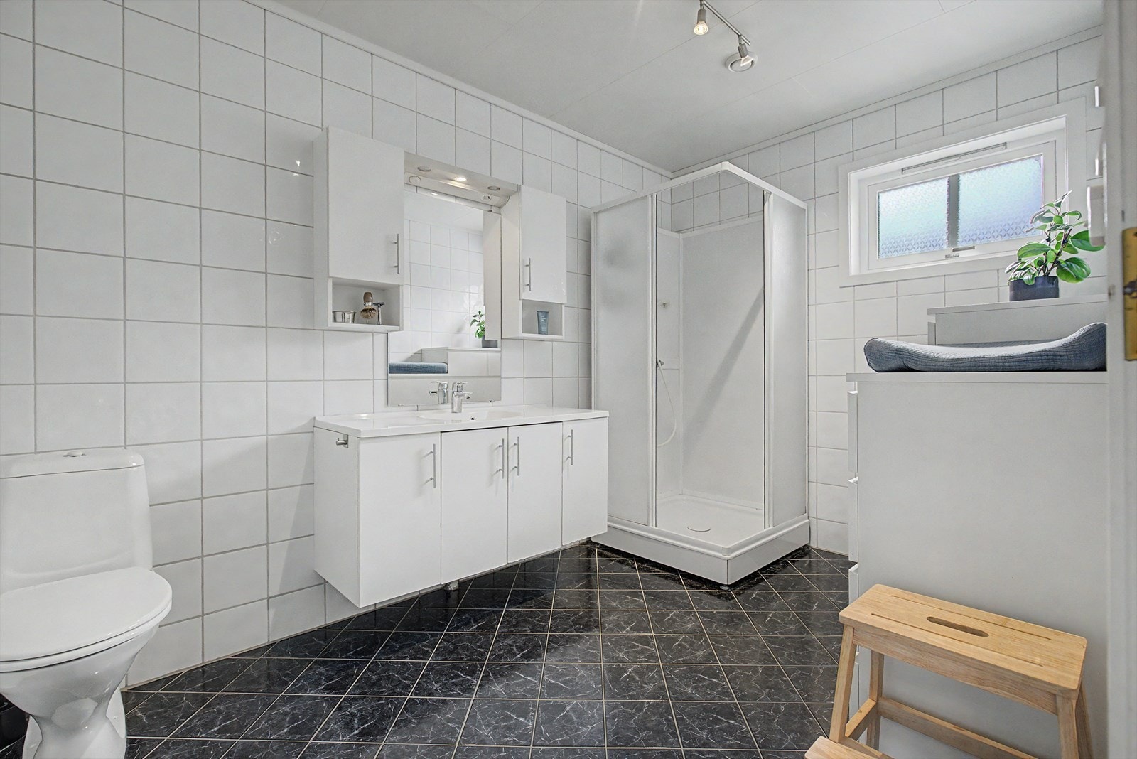 Romslig bad i hovedetasjen har flislagte gulv og vegger og er utstyrt med wc, baderomsinnredning og dusjkabinett Galleribilde