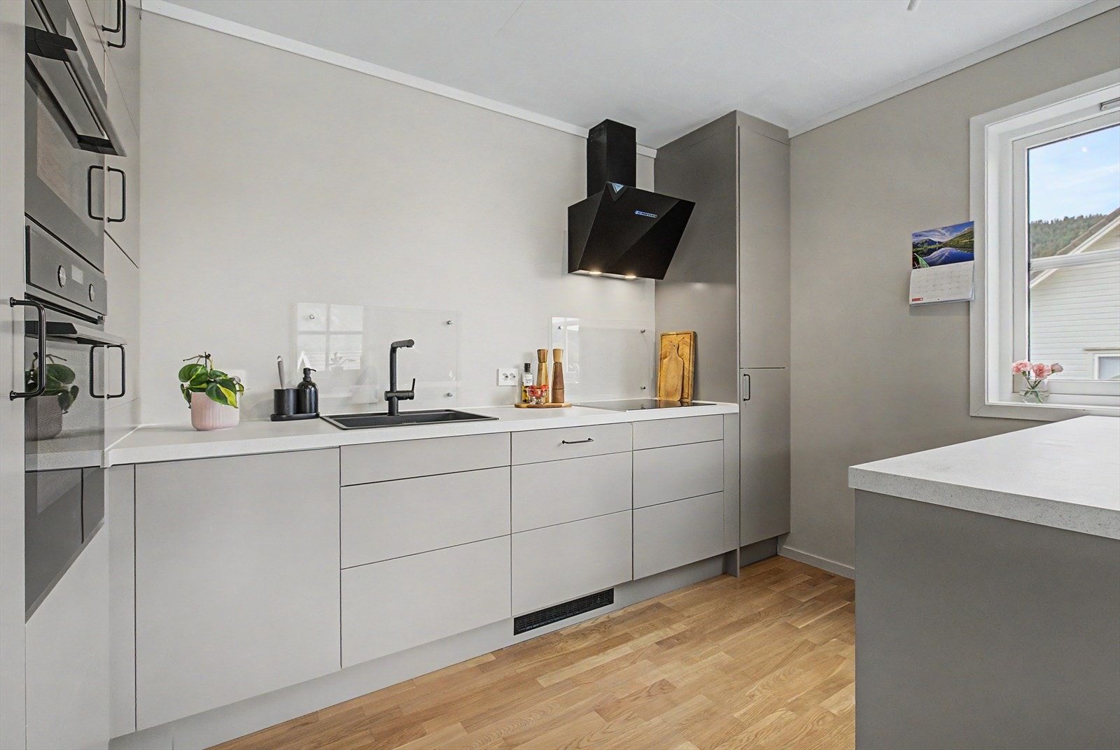 Innredning fra Epoq med malte skapfronter og takhøye skap | laminat benkeplater med nedfelt vask og platetopp | glassplater på vegg ved vasken og platetoppen | Integrert kombi/mikroovn, stekeovn, oppvaskmaskin og kjøleskap Galleribilde