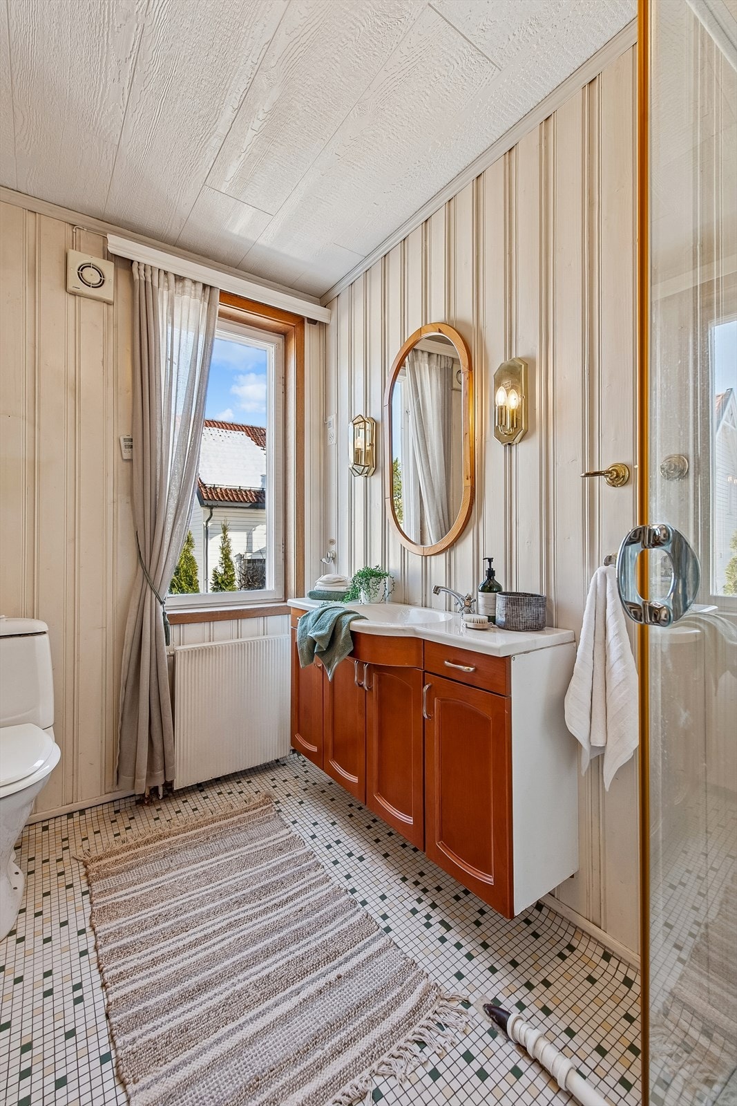 Badet i første etasje har vegger med malt panel og flislagt gulv. Galleribilde