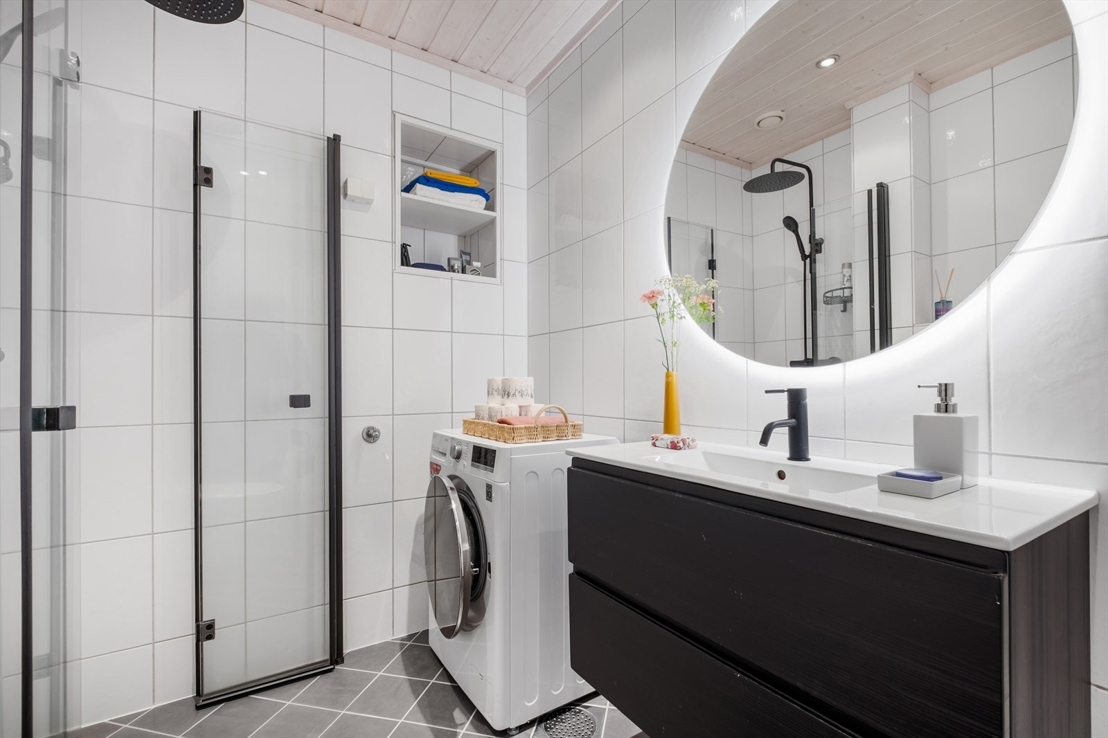Badet er utstyrt med dusjhjørne med innfellbare glassdører, veggmontert toalett og stilrent servantskap med glatte skuffefronter og overlimt servant gir et ryddig og helhetlig preg. Galleribilde