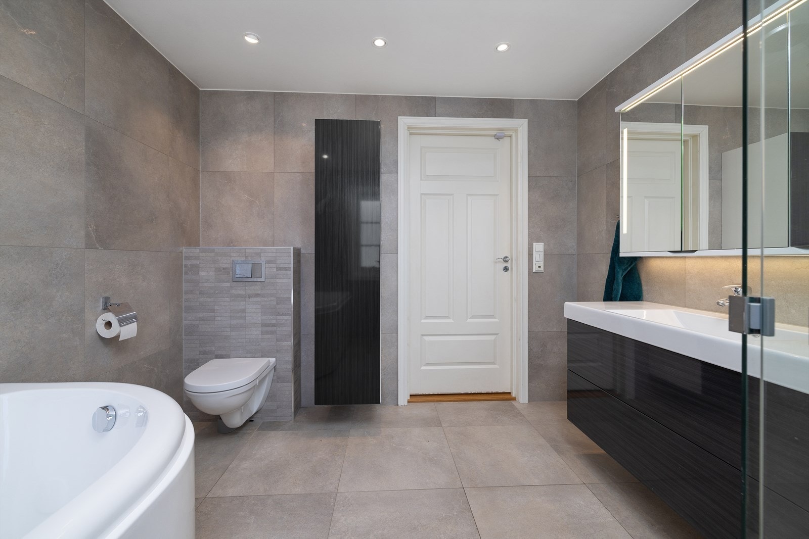 Badet er utstyrt med vegghengt toalett, downlights i taket og en stilren innredning med heldekkende servant og speilskap. Galleribilde