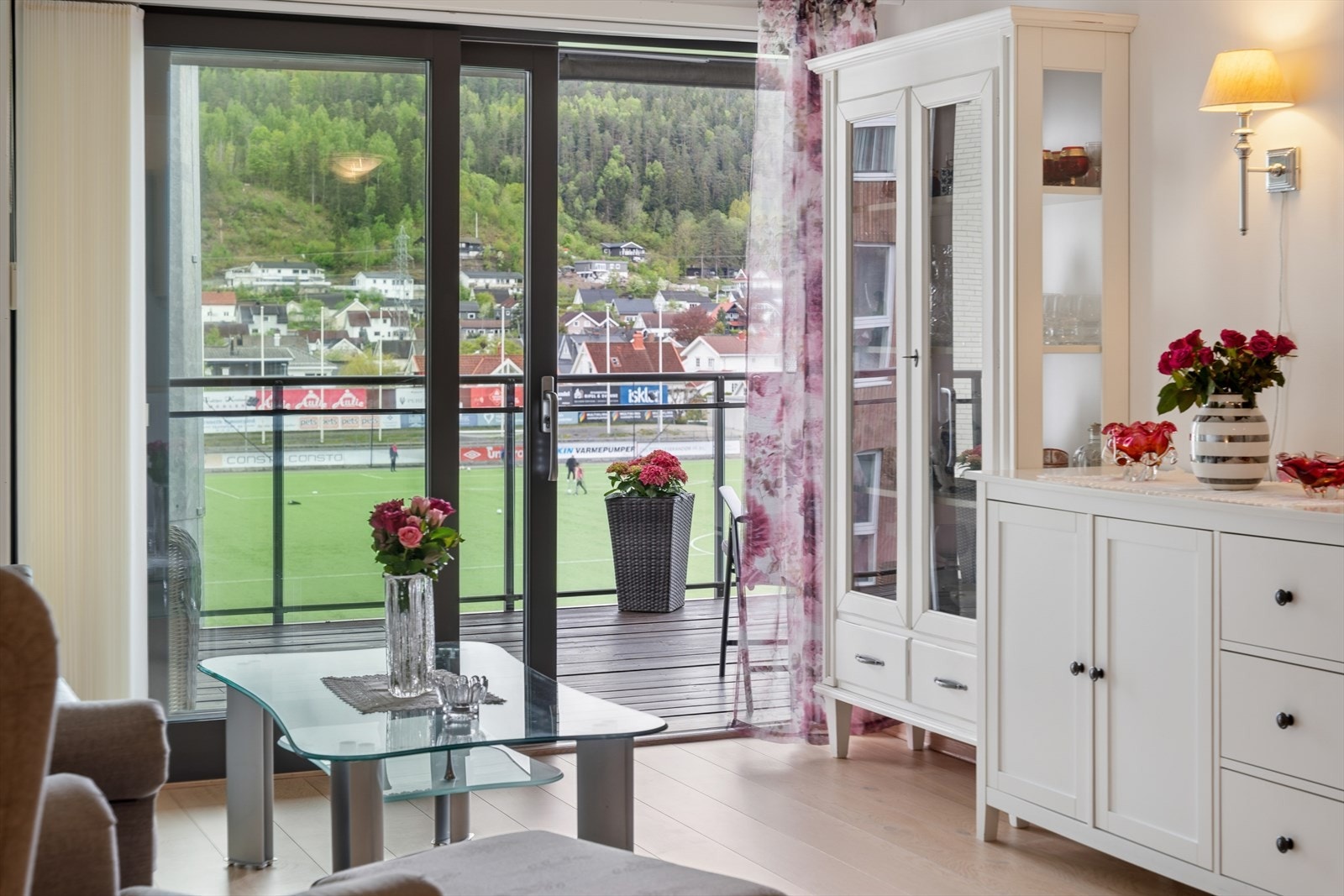 Store skyvedører i glass vender mot terrassen og slipper stadionutsikten inn i stuen. Galleribilde