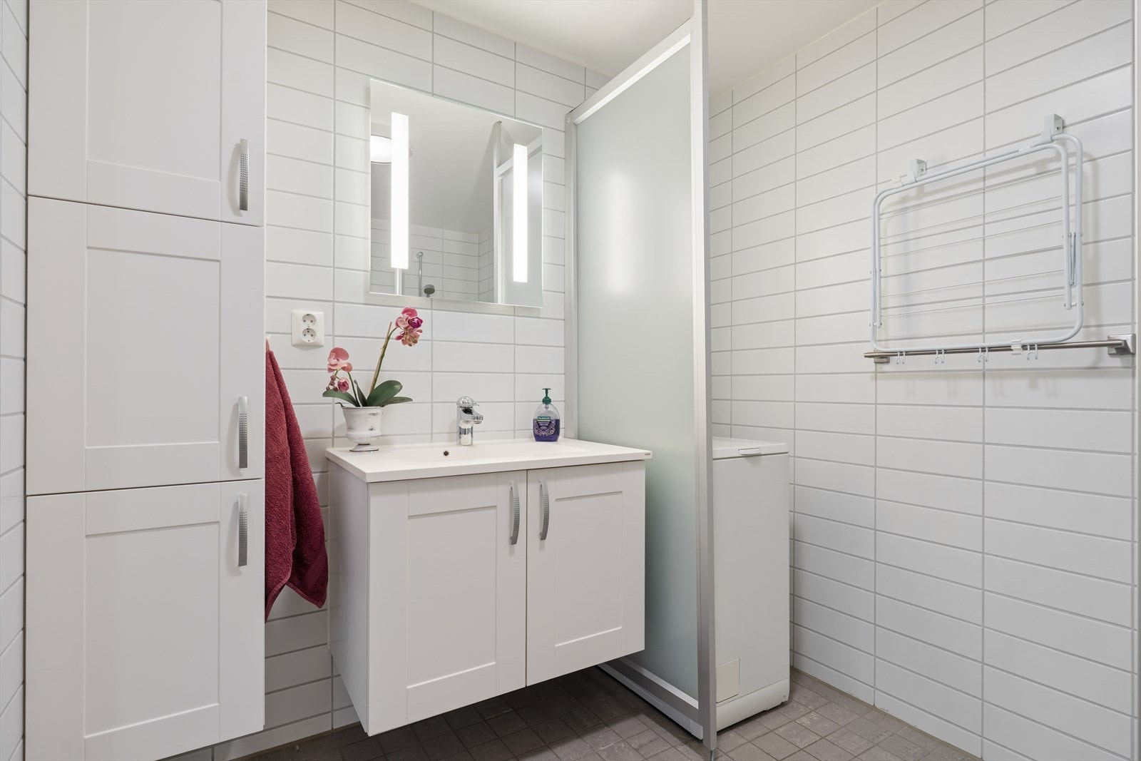 Badet er et flislagt og praktisk utformet baderom, innredet med dusjkabinett, toalett og baderomsinnredning med servant. Galleribilde