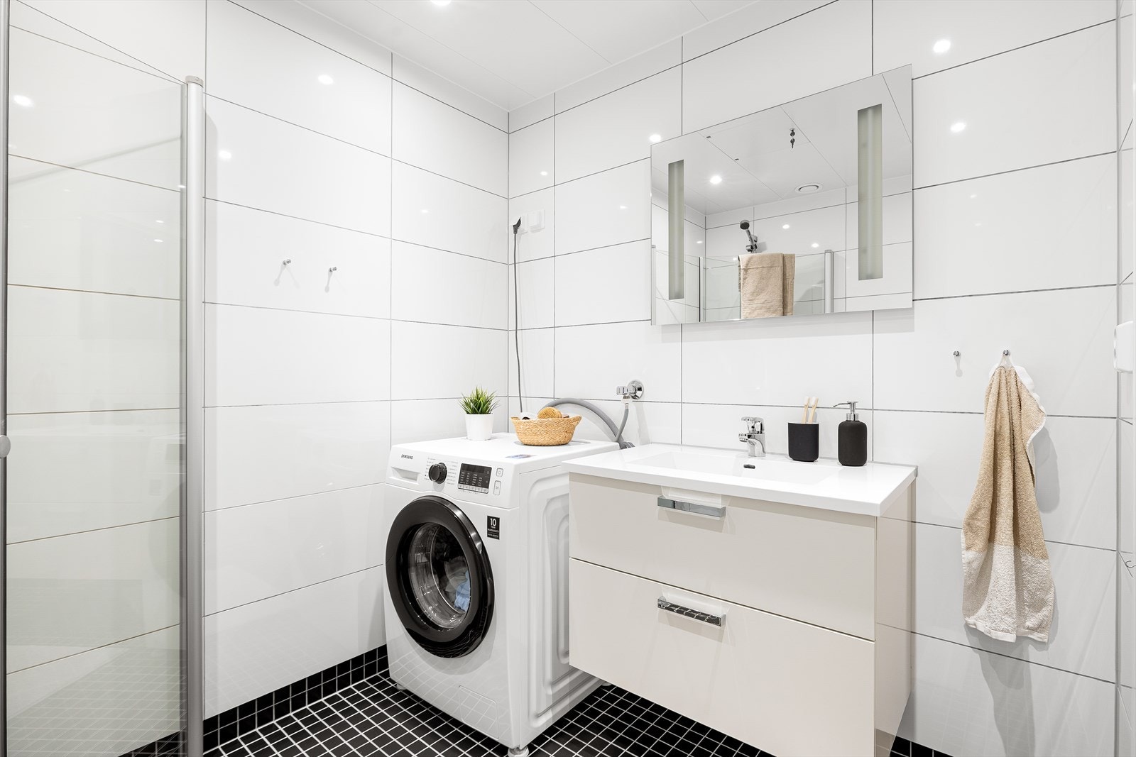 Badet er utstyrt med innfellbare dusjdører, mekanisk avtrekk, toalett, servant i skap, og opplegg for vaskemaskin/tørketrommel. Galleribilde