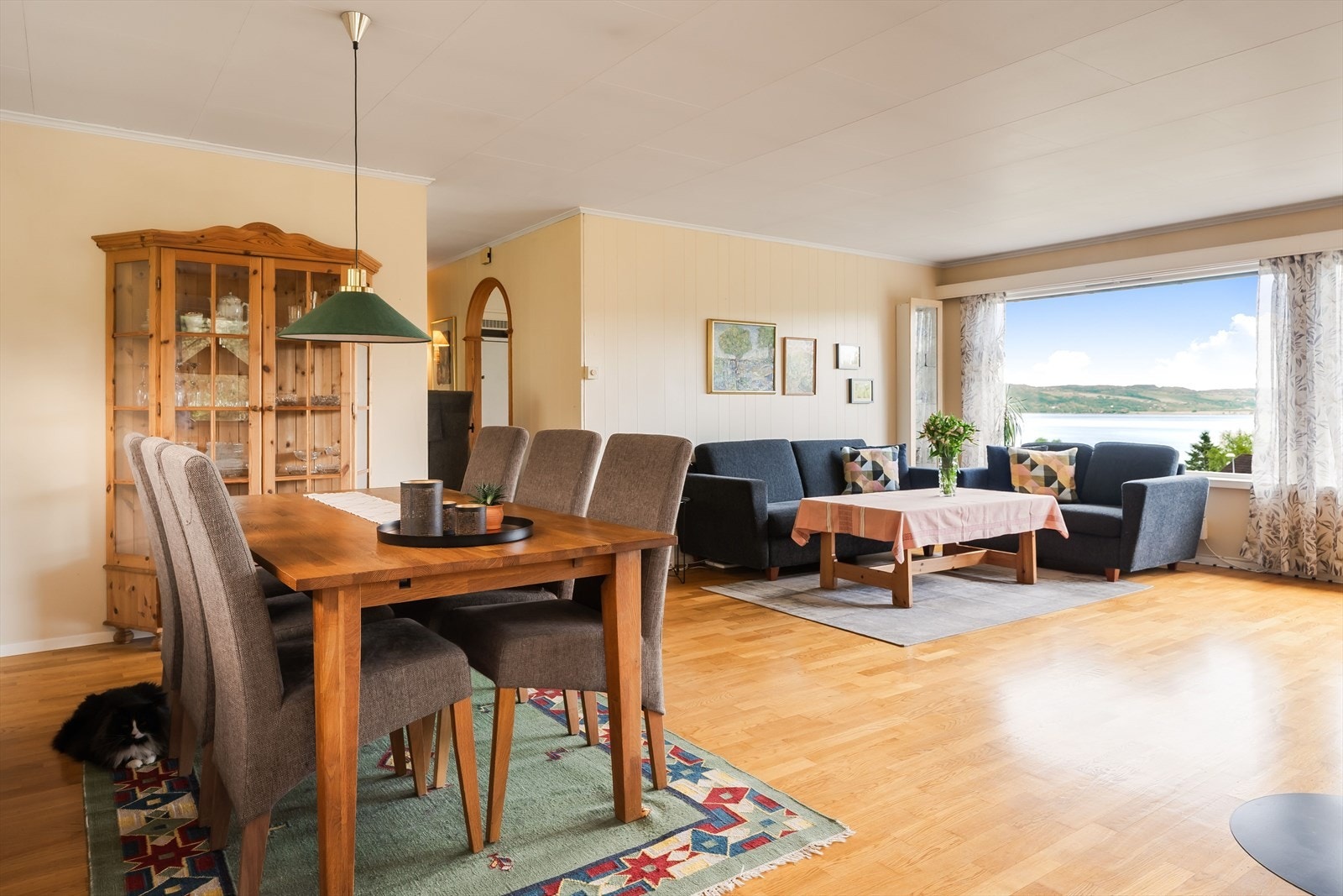 Stuen har en lun og tradisjonell atmosfære med lyse veggflater, parkett på gulv og god plassering av spiseplassen i tilknytning til vindusrekken. Galleribilde