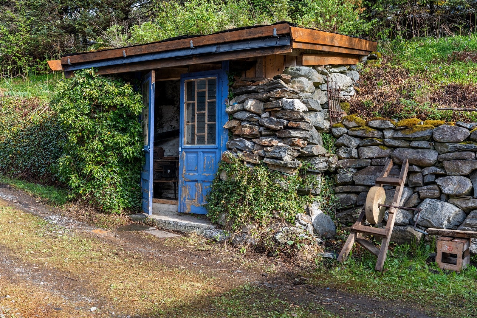 Sjarmerende steinbod/eldhus bygget inn i terrenget, med tak tekket med torv. Galleribilde