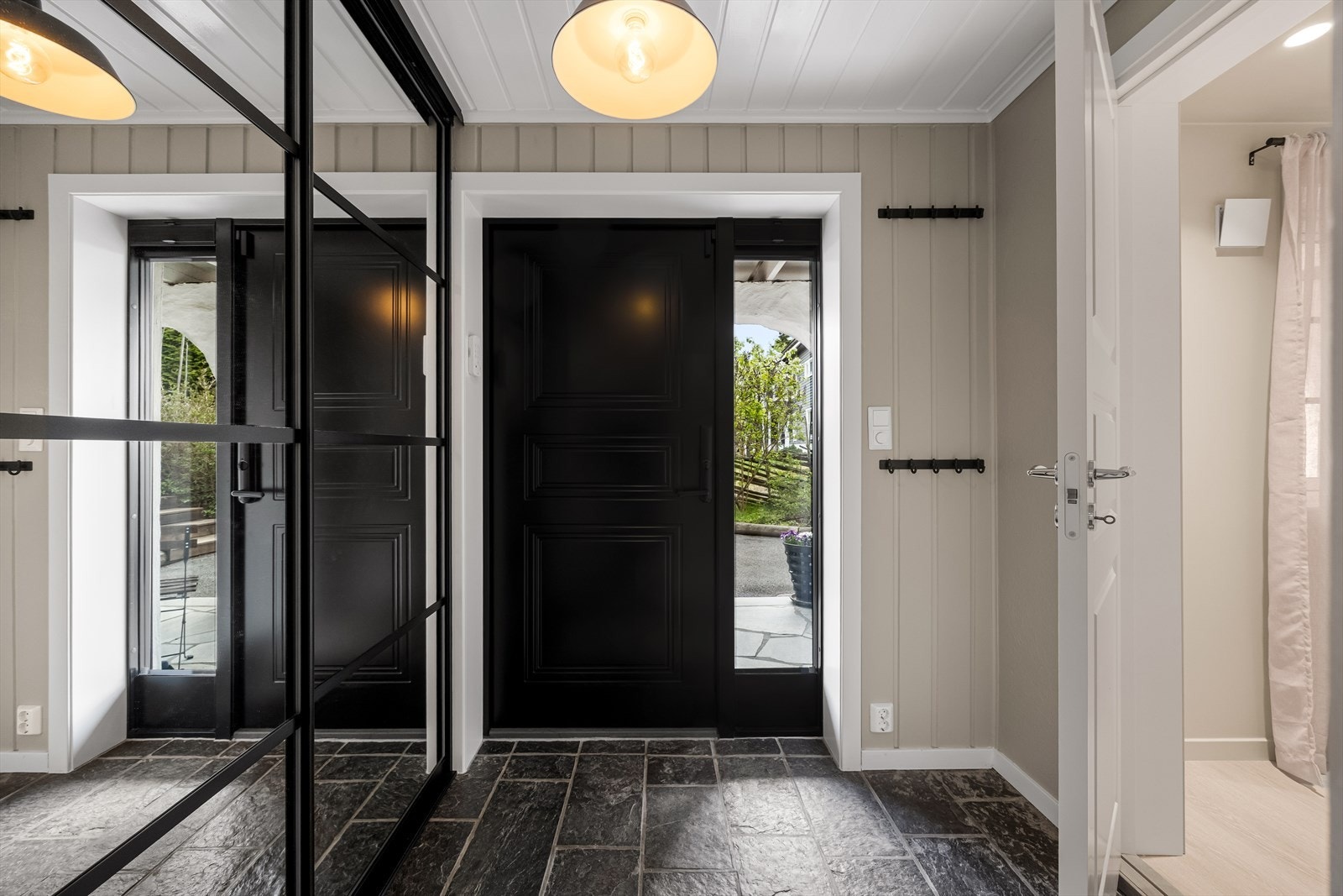 Entréen har flislagt gulv og god plass til oppbevaring av yttertøy i en stor skyvedørsgarderobe. Galleribilde