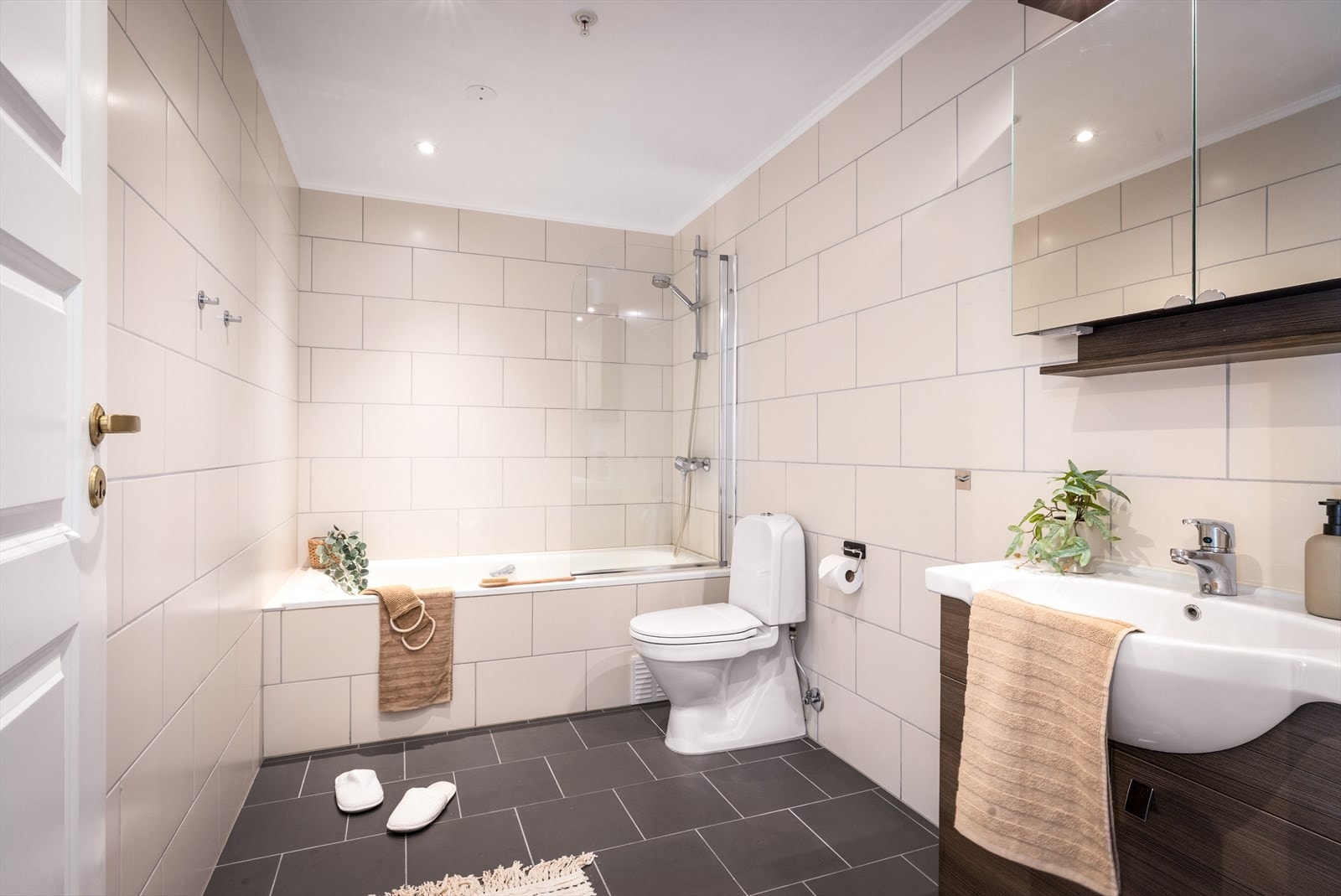 Pent bad innredet med wc, servant med møblement, speil, belysning og badekar. Galleribilde