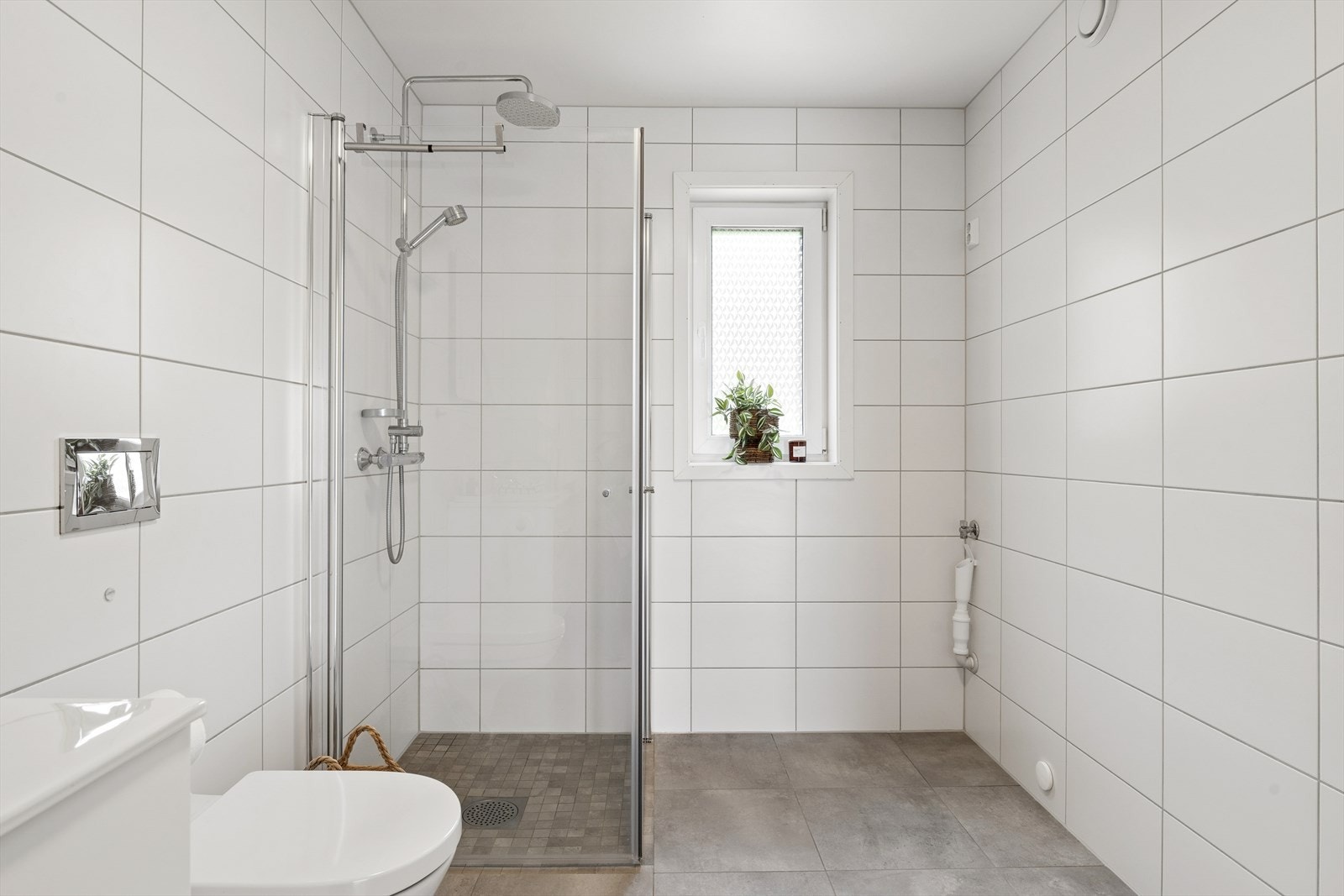 Badet er utstyrt med dusjhjørne med regndusj og hånddusj, vegghengt toalett og opplegg for vaskemaskin. Galleribilde