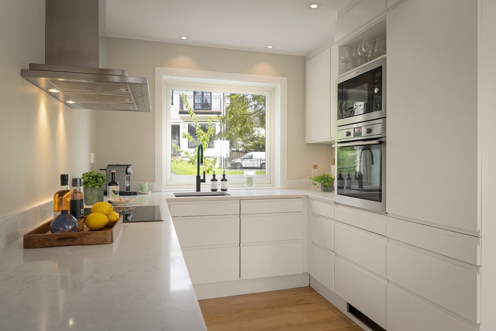 Kjøkken med tidsriktig glatt innredning fra Aubo, soft close og takoppføring. Innfelte downlights under overskap. Kompositt benkeplate med underlimt stålkum og nedfelt induksjonstopp. Integrert komfyr, oppvaskmaskin samt kjøl/frys Galleribilde