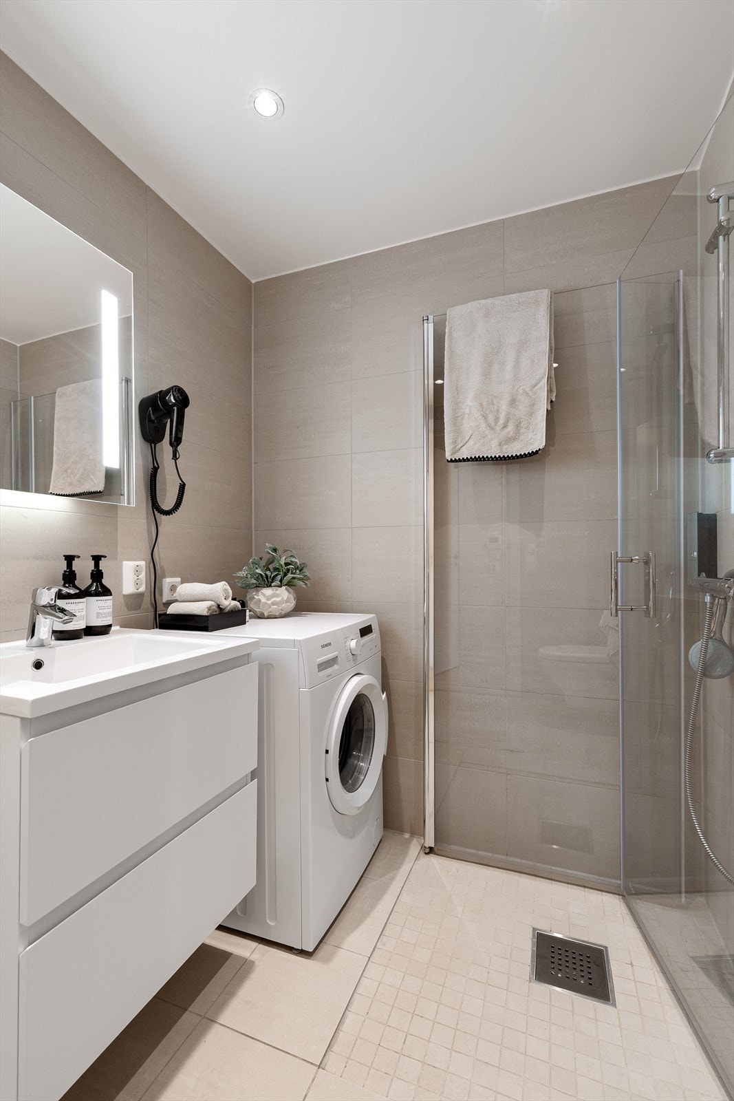 Badet har servant med underskap, speil med belysning og opplegg for vaskemaskin. Galleribilde