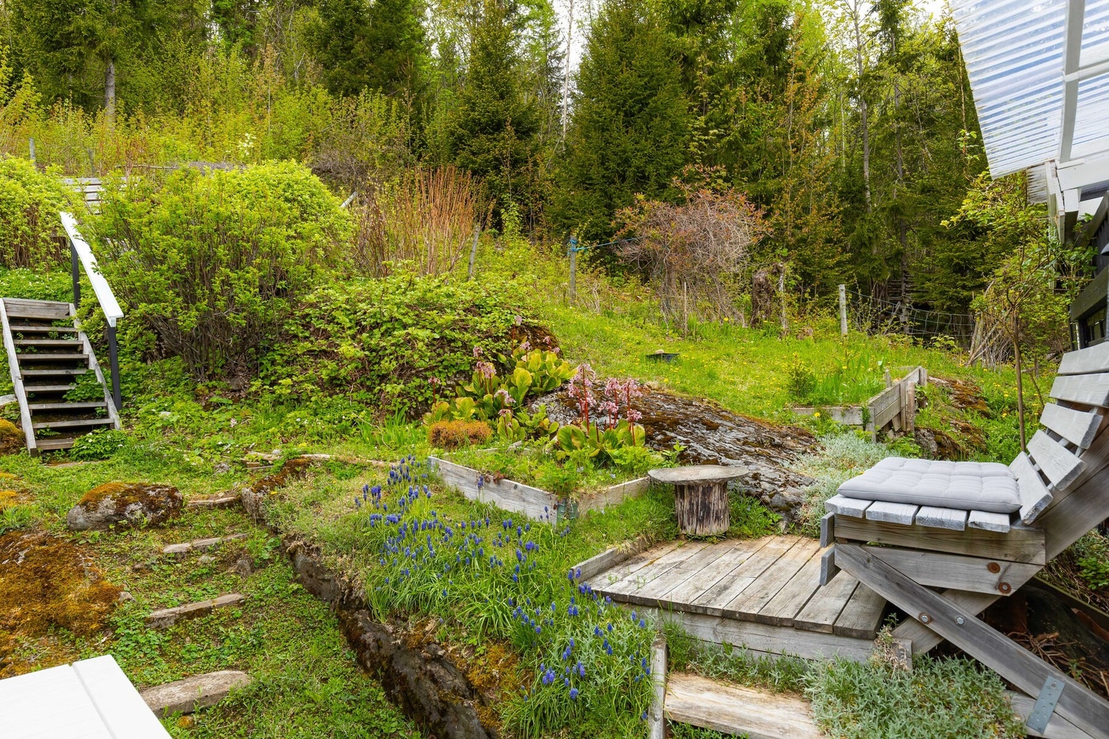 Pent opparbeidet tomt med prydbusker, blomster og sitteplasser. Galleribilde