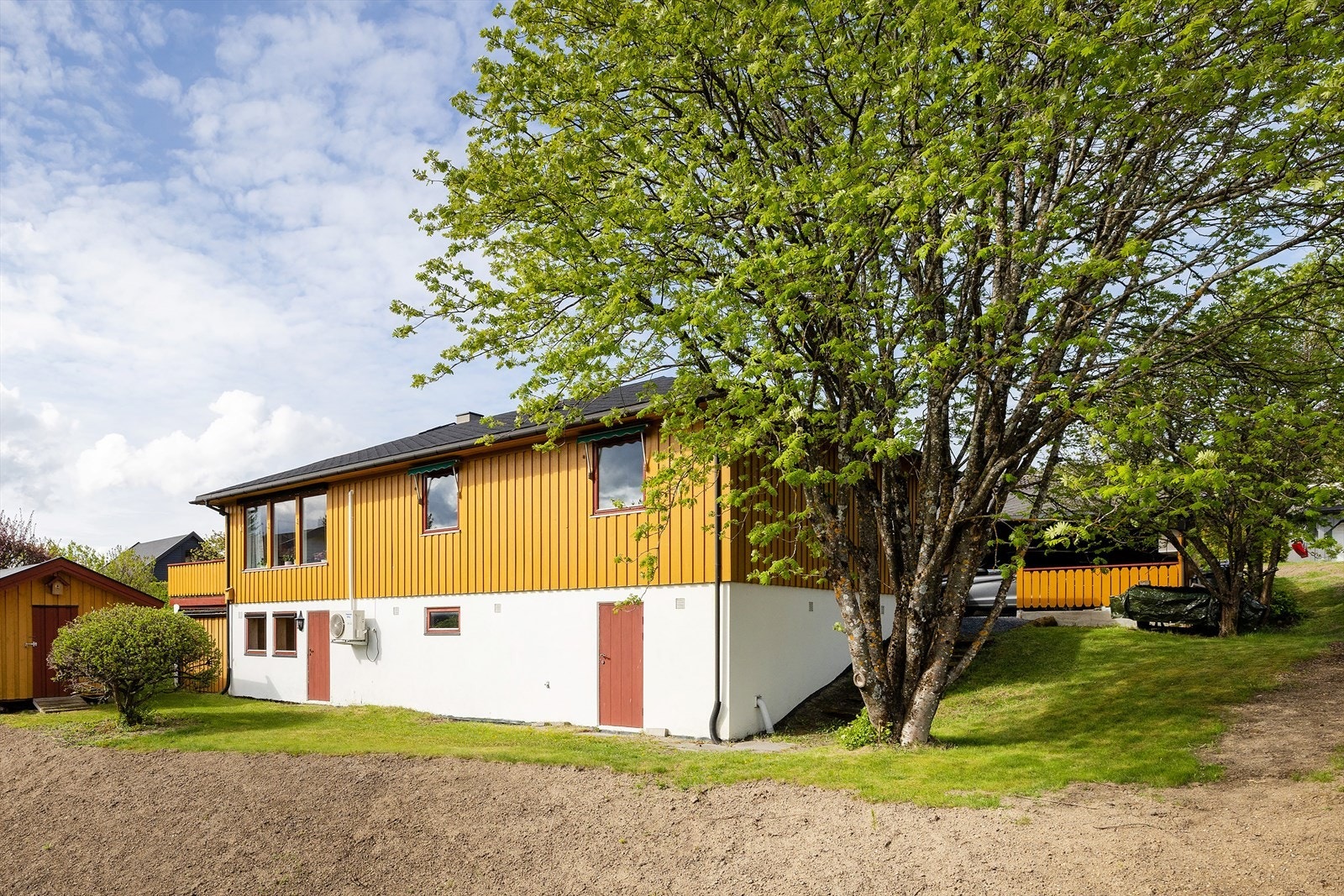 Enebolig over to plan med frittstående carport og uthus. Yttertaket er tekket med shingel fra 2018. Gammel beplantning er fjernet i skråningen. Området er delvis nysådd, noe som samtidig gir mulighet for ny beplantning. Galleribilde