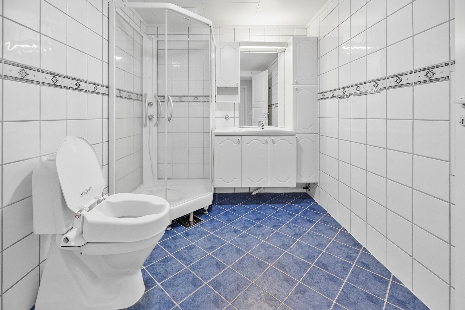 Badet er utstyrt med servantinnredning, toalett og dusjkabinett. Galleribilde