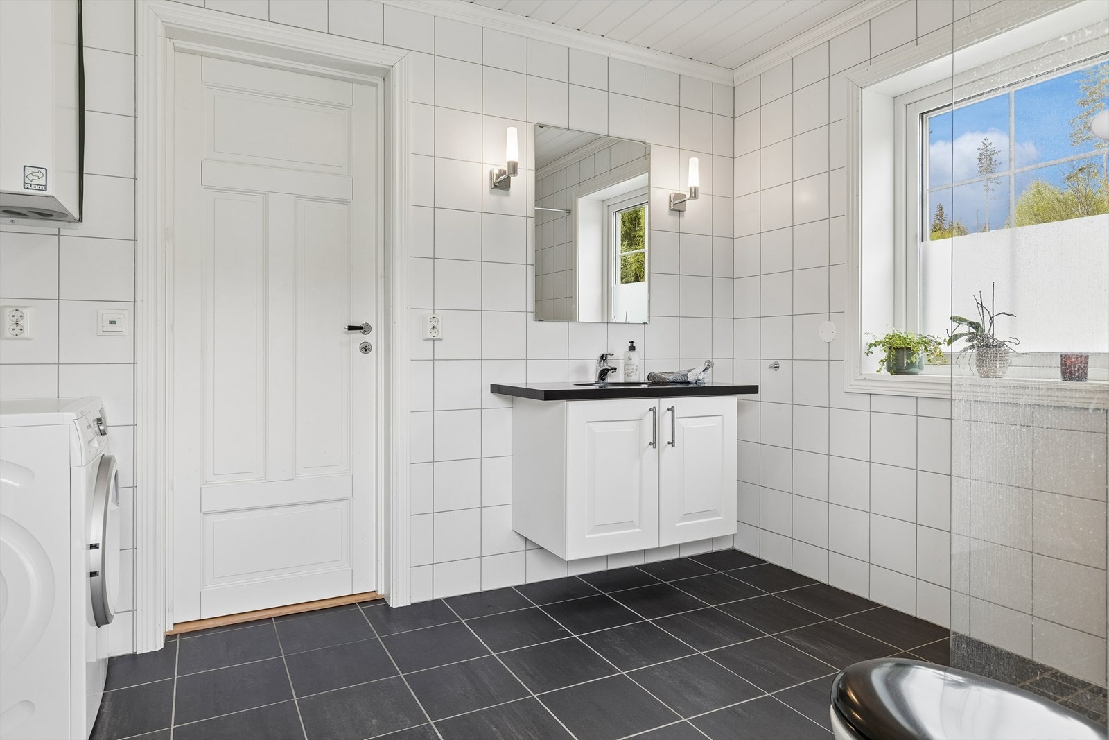 Badet i første etasje er flislagt og har servantinnredning og opplegg for vaskemaskin. Galleribilde